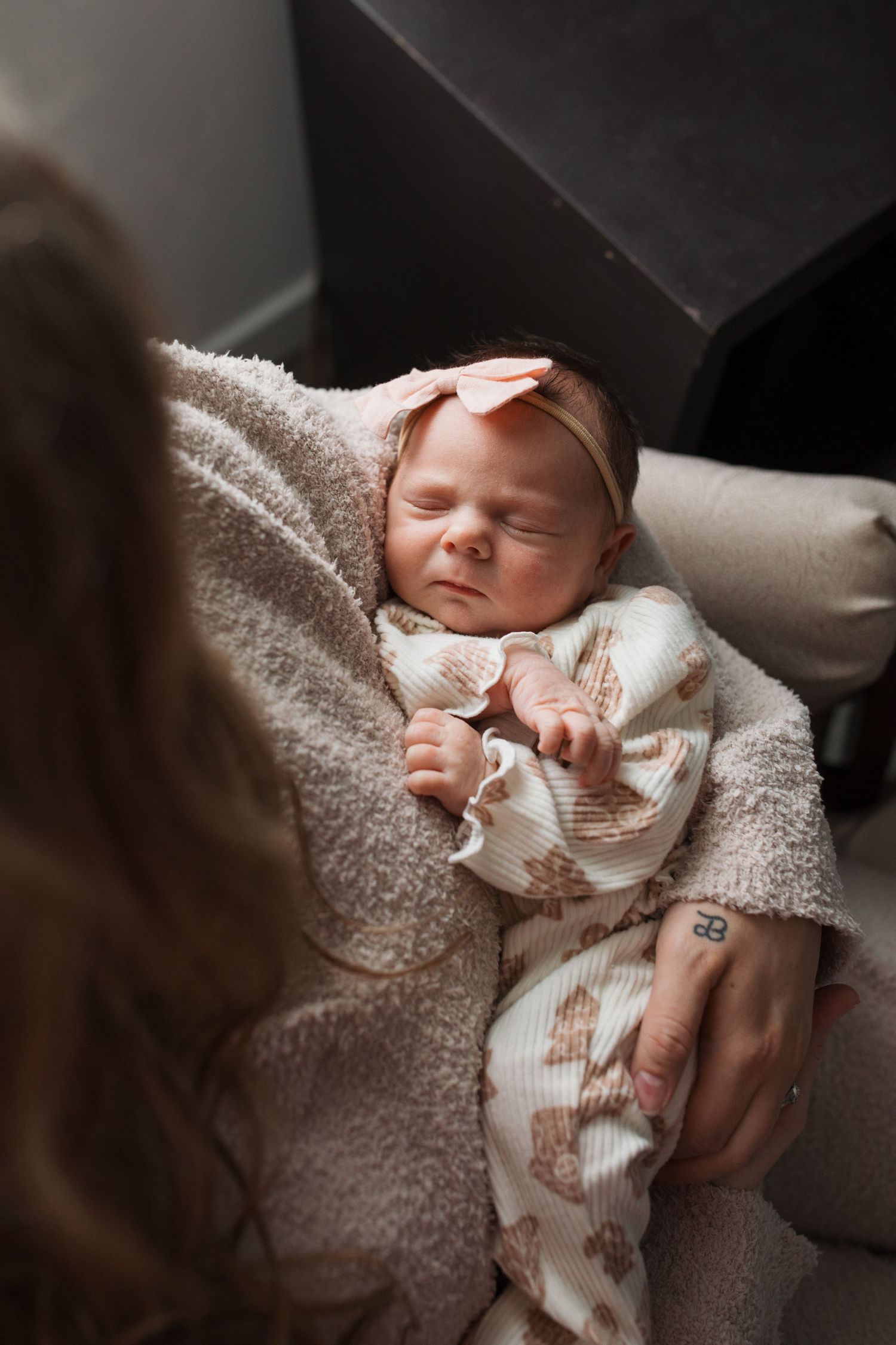 Mother holding her newborn baby girl in soft natural window light during an in-home lifestyle session in Middleton, Idaho.
