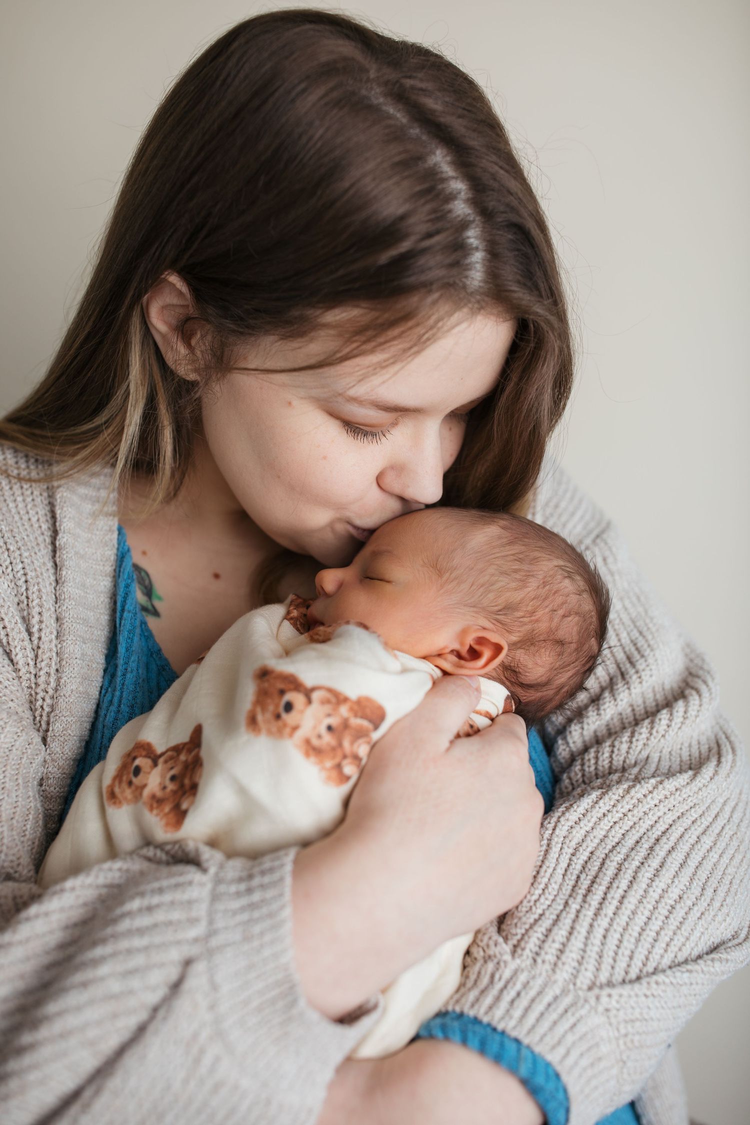 Mother kissing her newborn baby boy during cozy studio newborn session in the Treasure Valley