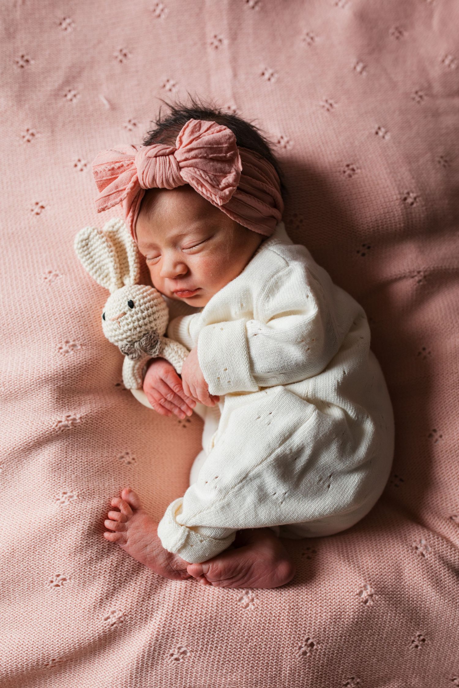 Sleeping newborn baby girl with bow and bunny on hospital bed during Fresh 48 session
