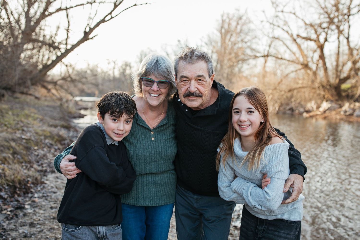 Grandparents smiling with their grandchildren during a lifestyle family photography session by the river in Idaho