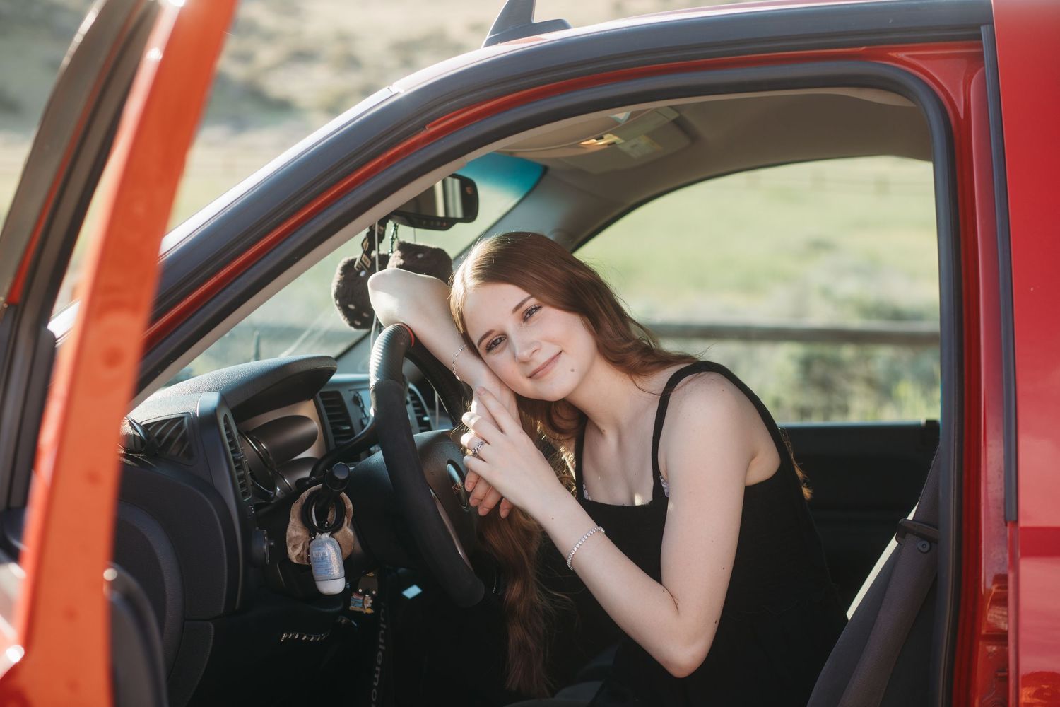 Boise senior photos of high school girl smiling inside red truck during golden hour outdoor senior session