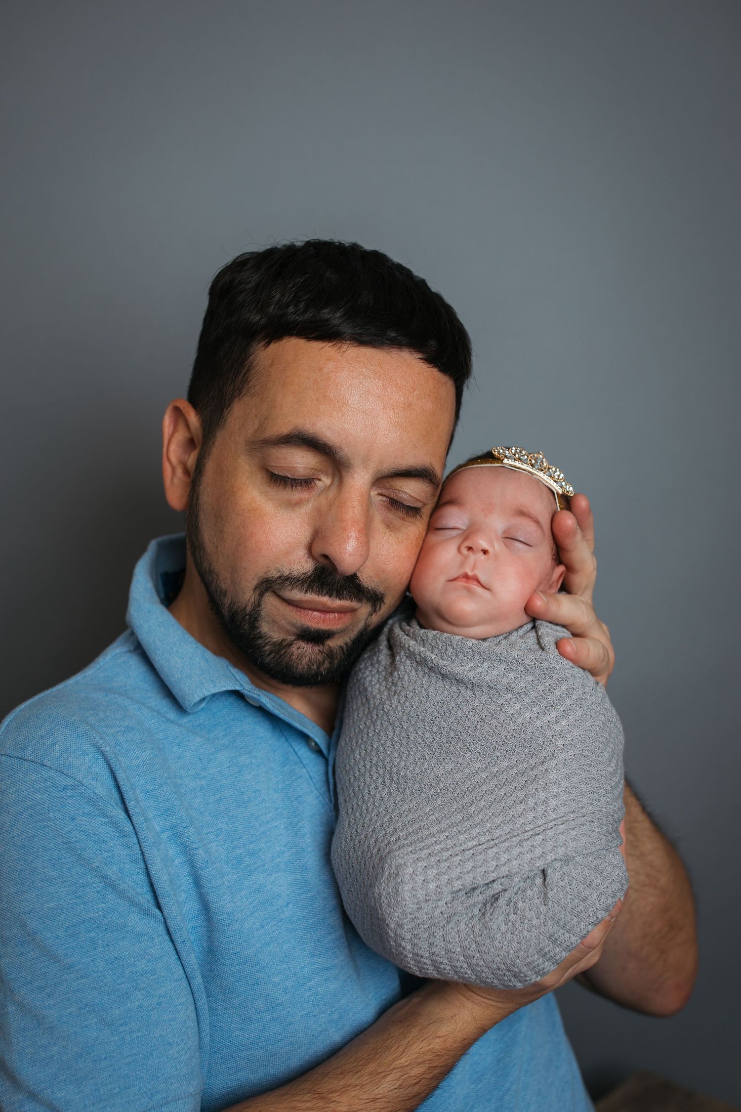 Dad cuddling his sleeping newborn baby girl during a studio newborn session in Nampa, Idaho