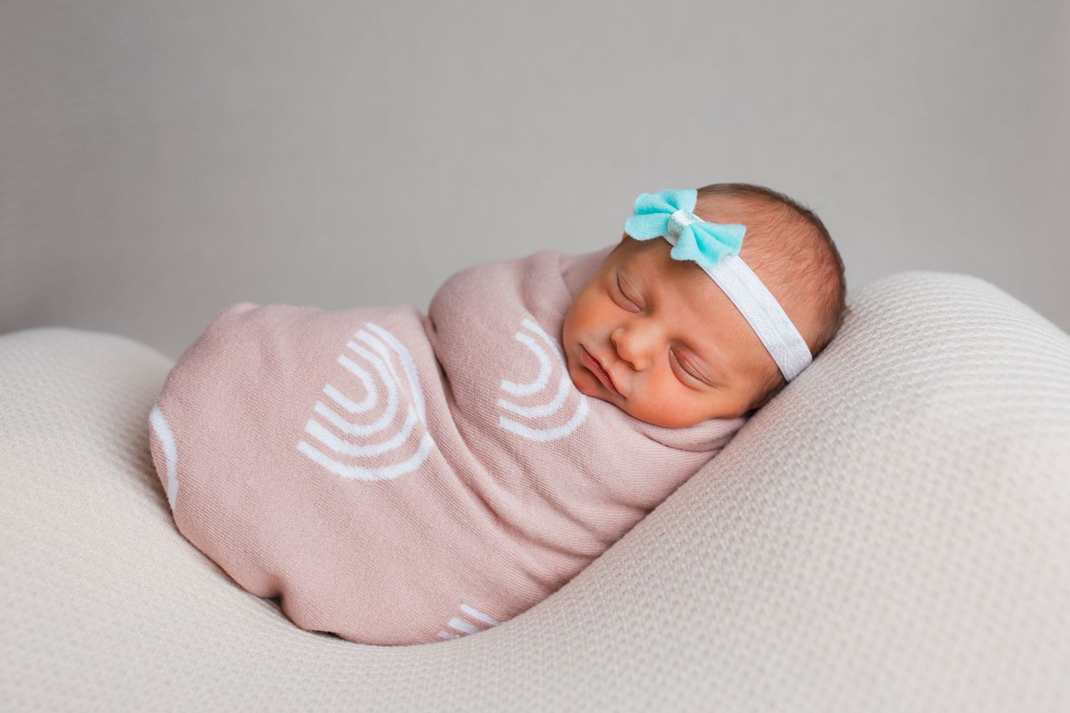 Newborn baby girl wrapped in a soft pink rainbow blanket during a studio newborn photography session in Nampa, Idaho.