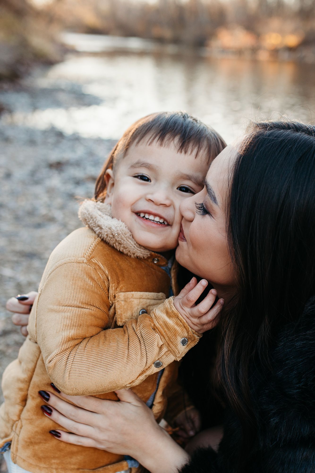 A tender moment of affection and laughter shared between parent and child outdoors in warm autumn light - lifestyle family photos in Boise