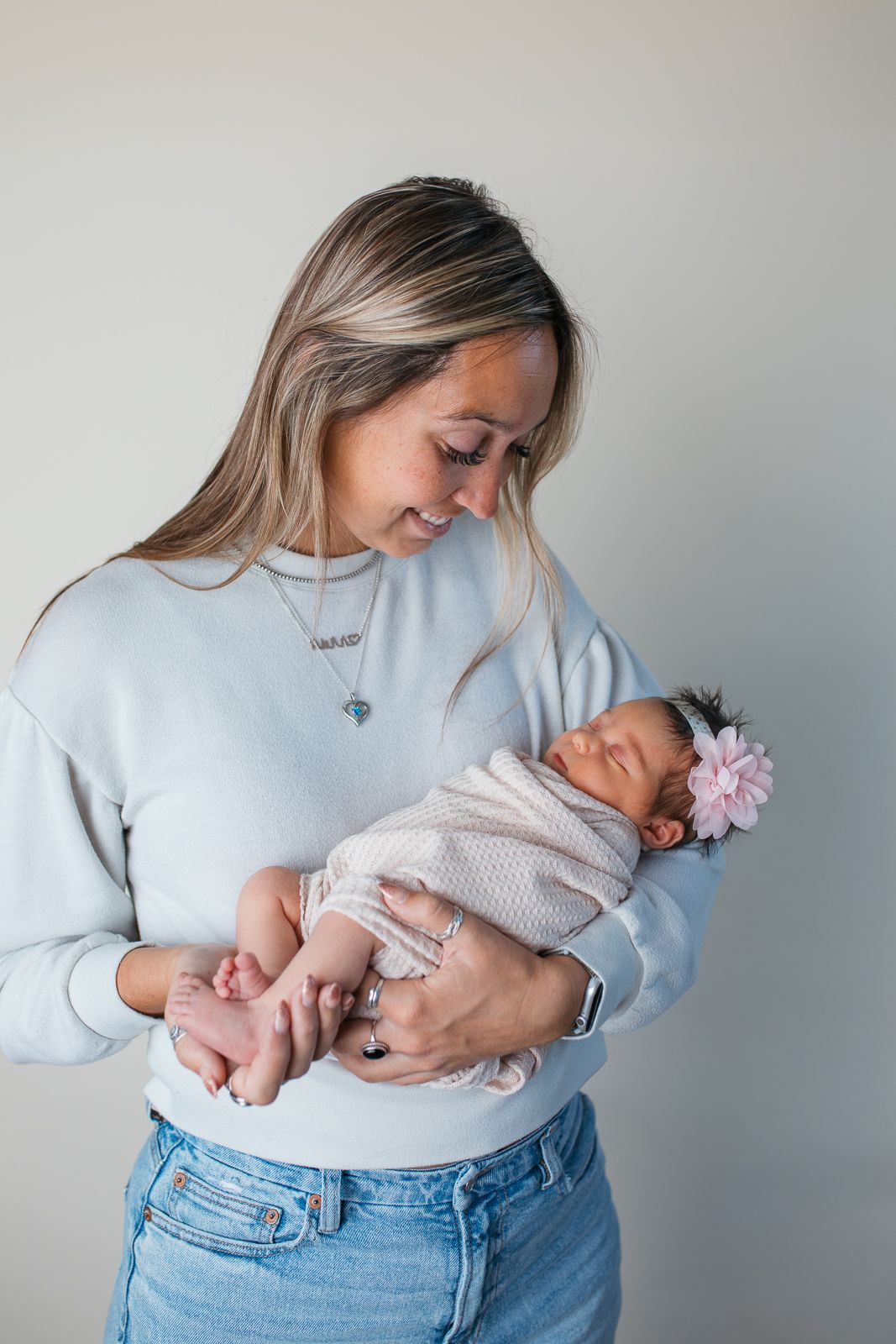 A series of tender moments showing a parent cradling and bonding with a newborn baby while wearing a light blue sweater  studio newborn
