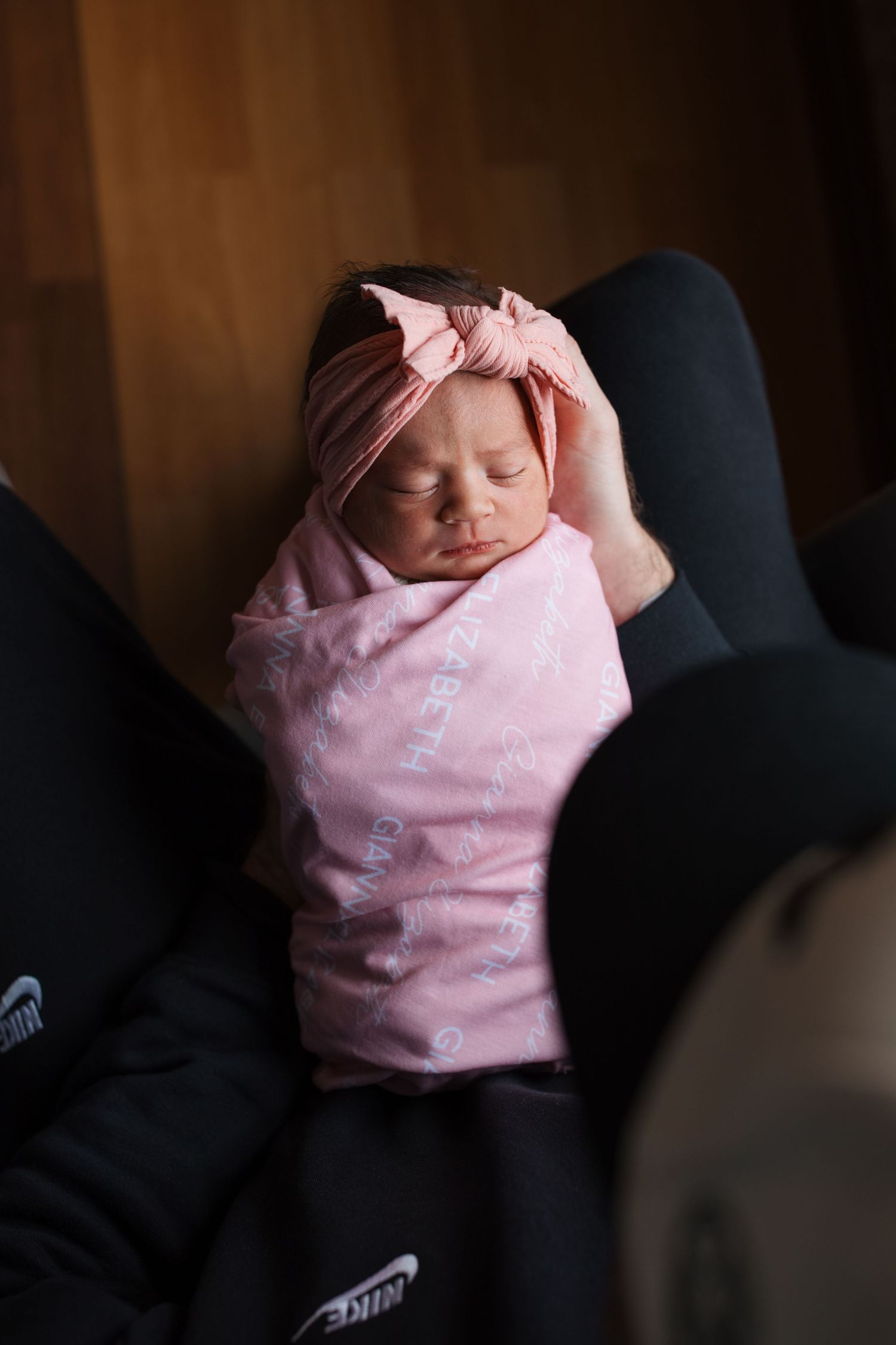 Newborn baby girl wrapped in pink swaddle on parent’s lap during Boise Fresh 48 hospital session