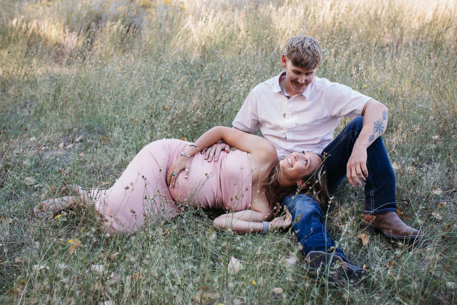 A sequence of romantic outdoor photos showing an expectant couple lying in a grassy meadow during golden hour - Maternity session in Boise