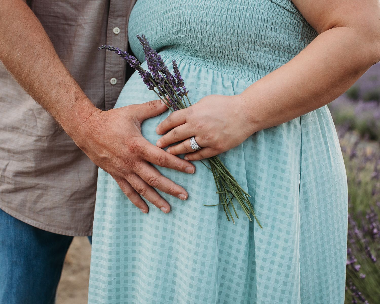 A couple in coordinated mint and gray outfits stand close together while posing outdoors - Maternity session in Boise, Idaho