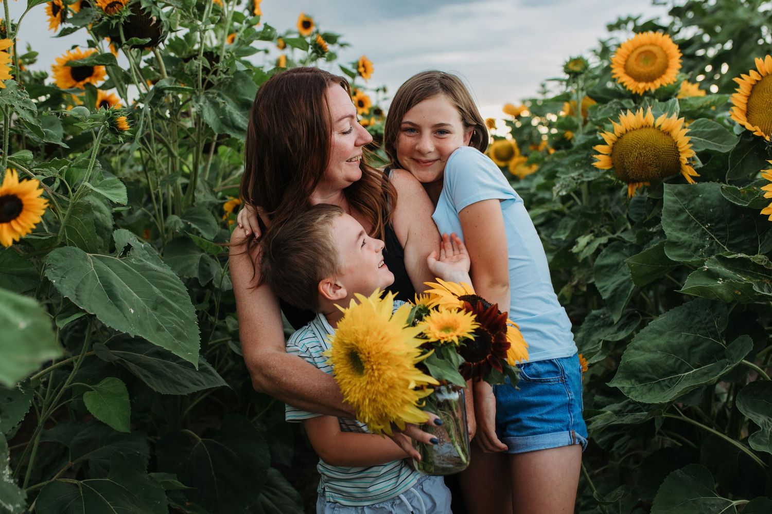 Mom hugging her two children during a sunflower field family session in Boise.
