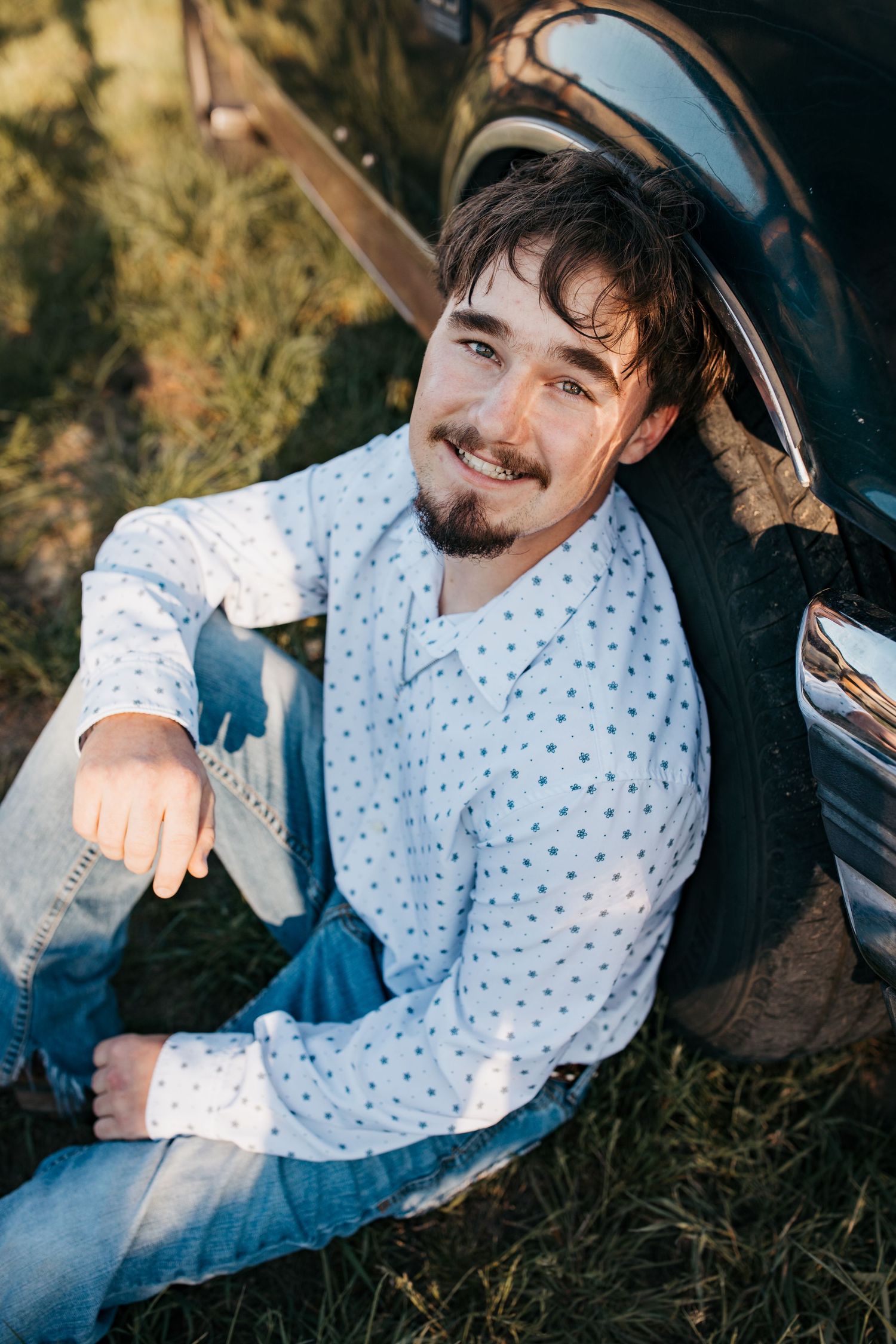 Close up senior portrait of high school boy sitting by truck tire during Boise Idaho senior photo session