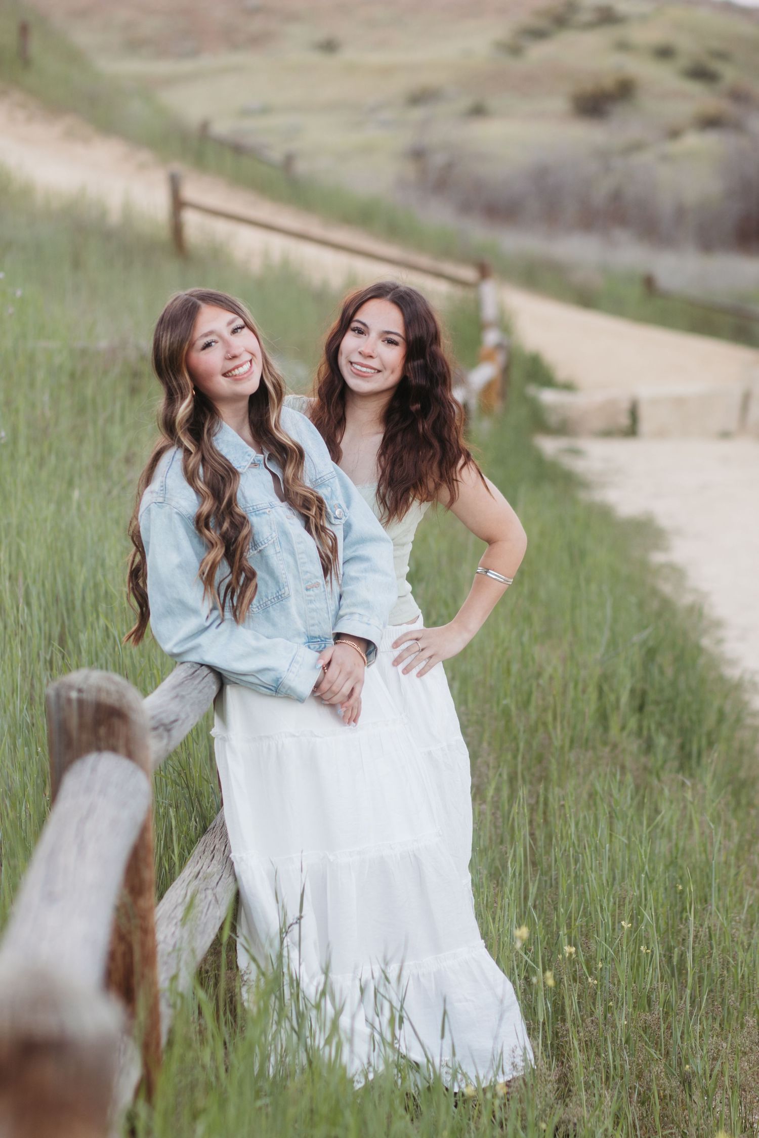 Two high school seniors posing together by fence during Boise senior photo session
