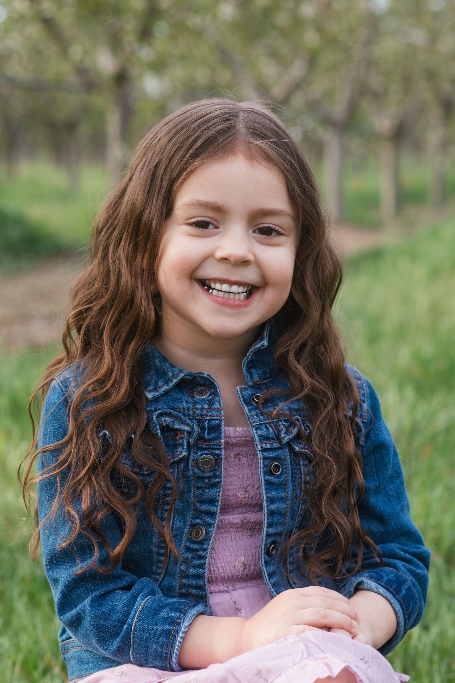 Smiling young girl portrait in blossom orchard during spring family session in Caldwell Idaho
