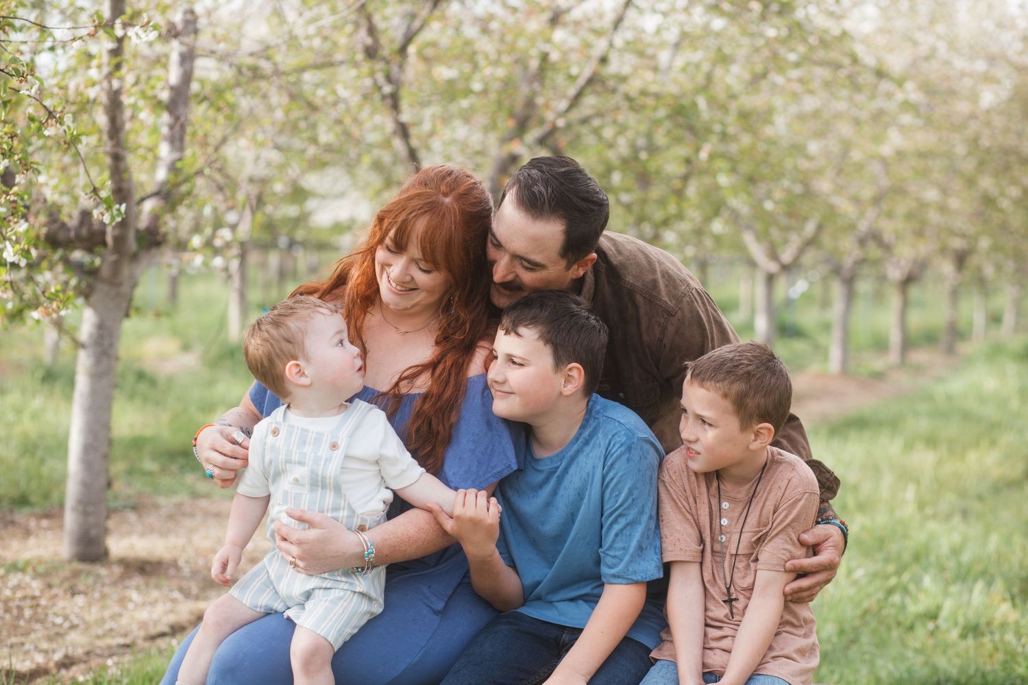 Family smiling together under white cherry blossoms at Cherry Hill Farms in Caldwell, Idaho