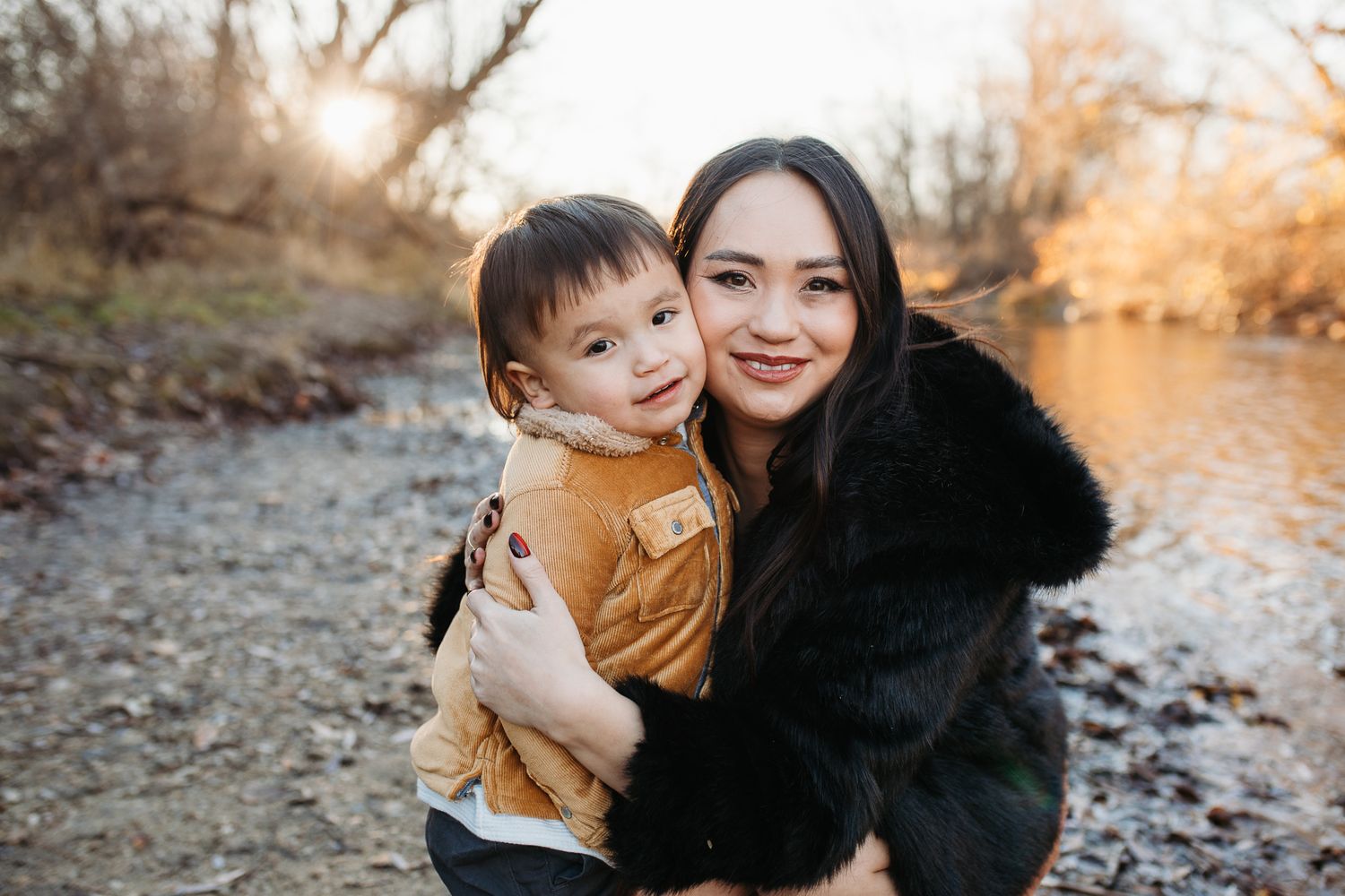 A series of outdoor family portraits taken at sunset by a river with autumn colors in the background - lifestyle family photos in Boise
