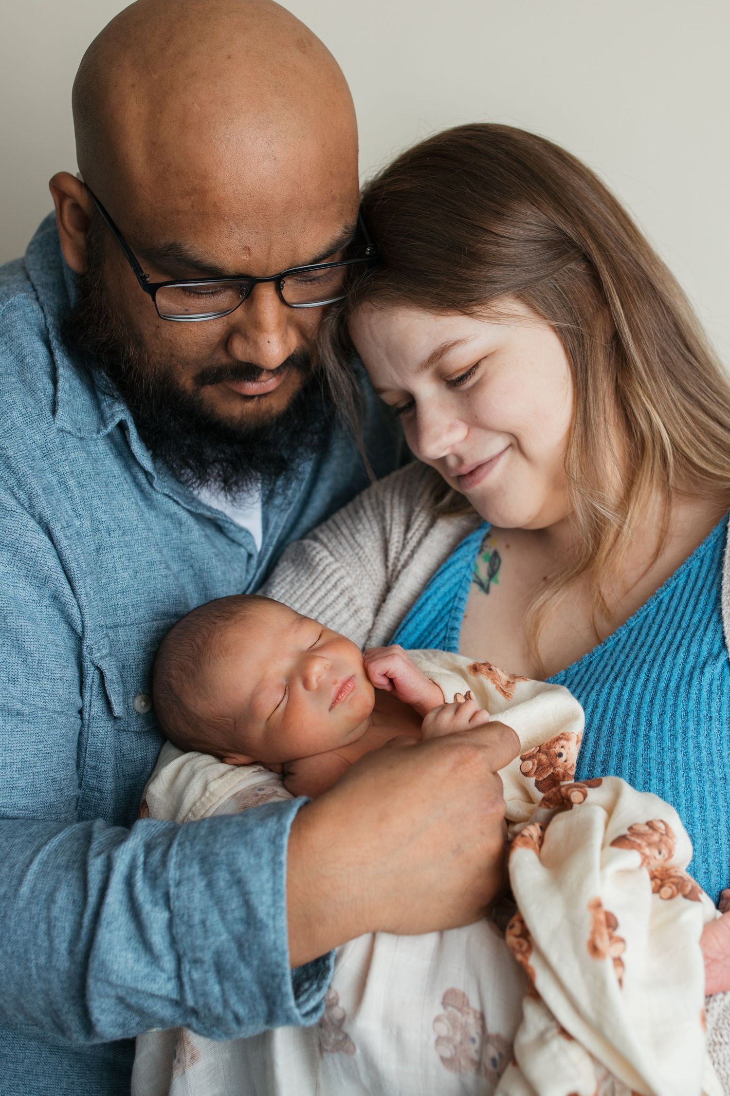 Parents holding their newborn baby boy together in a warm studio newborn family portrait