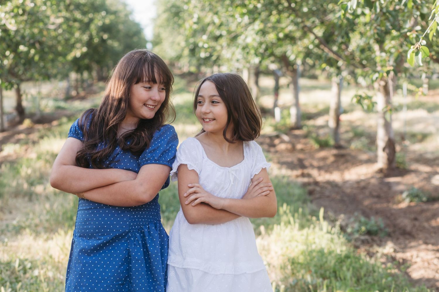 Sisters smiling at each other during a relaxed outdoor family session in Boise, Idaho.