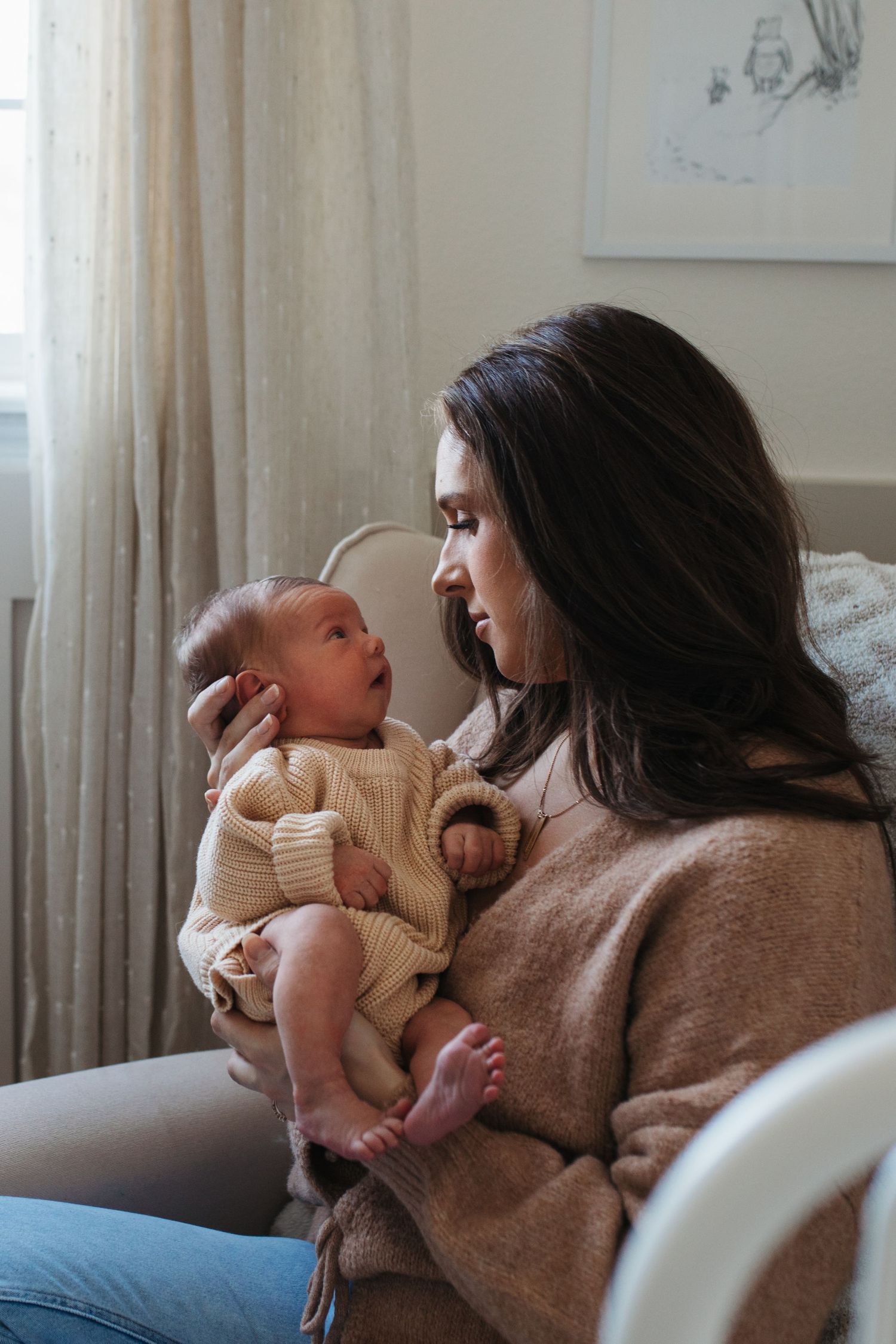 A tender moment between parent and baby relaxing together in a rocking chair in warm natural light - lifestyle in-home newborn photos Boise