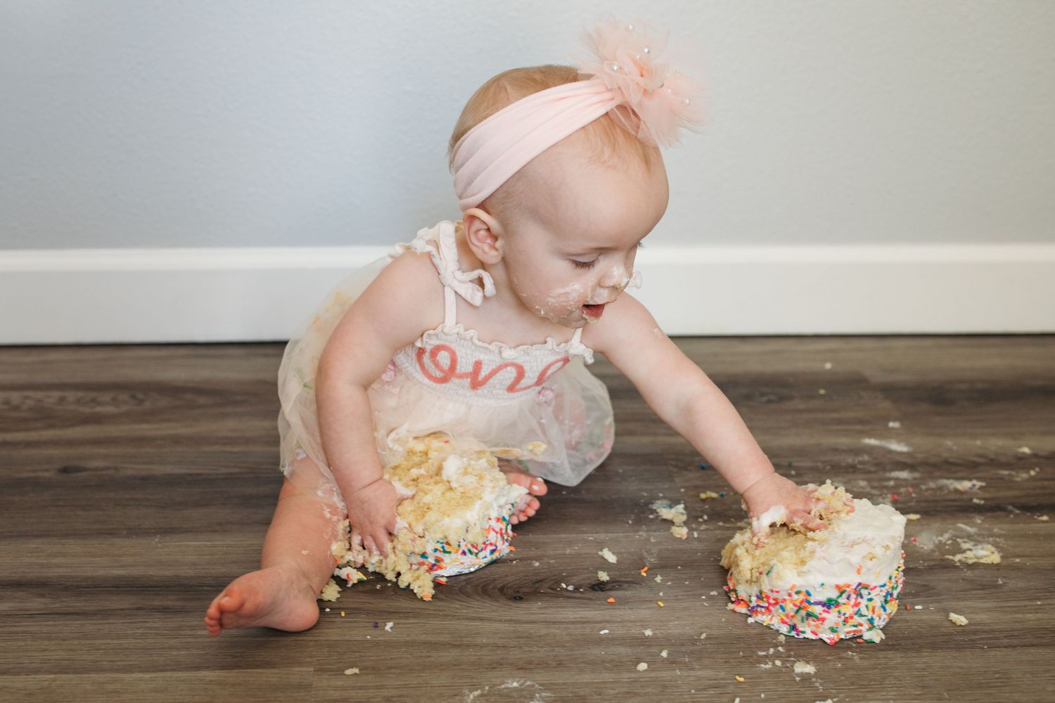 One year old girl enjoying her first birthday cake smash during a lifestyle milestone session in Kuna Idaho.
