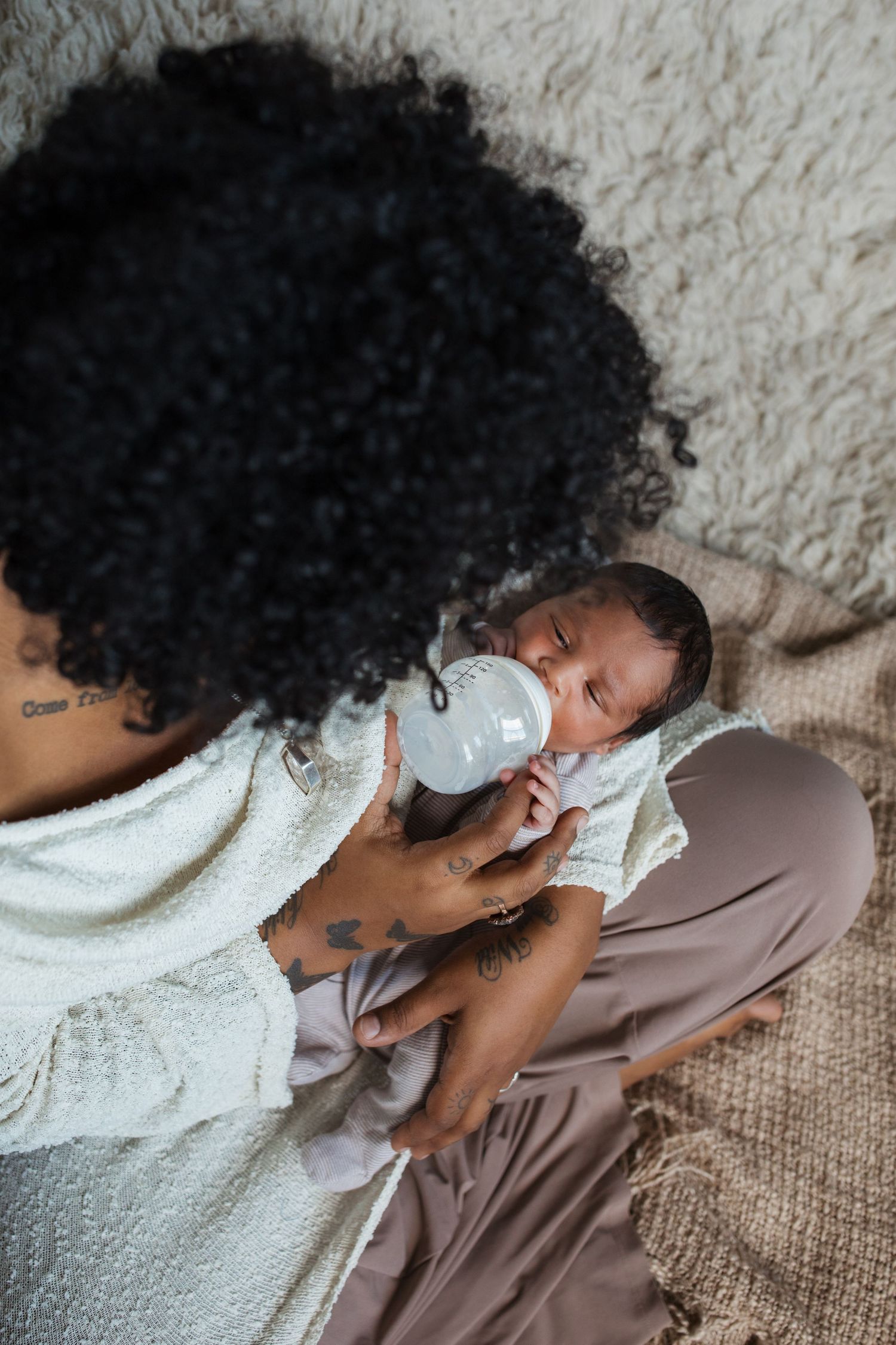 Mother feeding her newborn baby with a bottle during a lifestyle newborn photography session in the Treasure Valley.