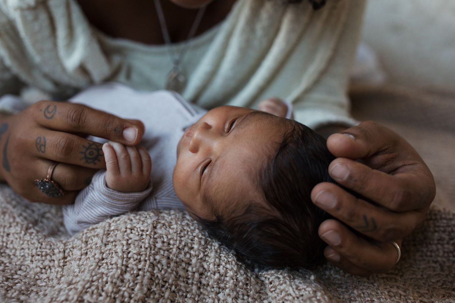 Close-up of newborn baby resting in mother's hands during a lifestyle newborn photography session in the Treasure Valley.