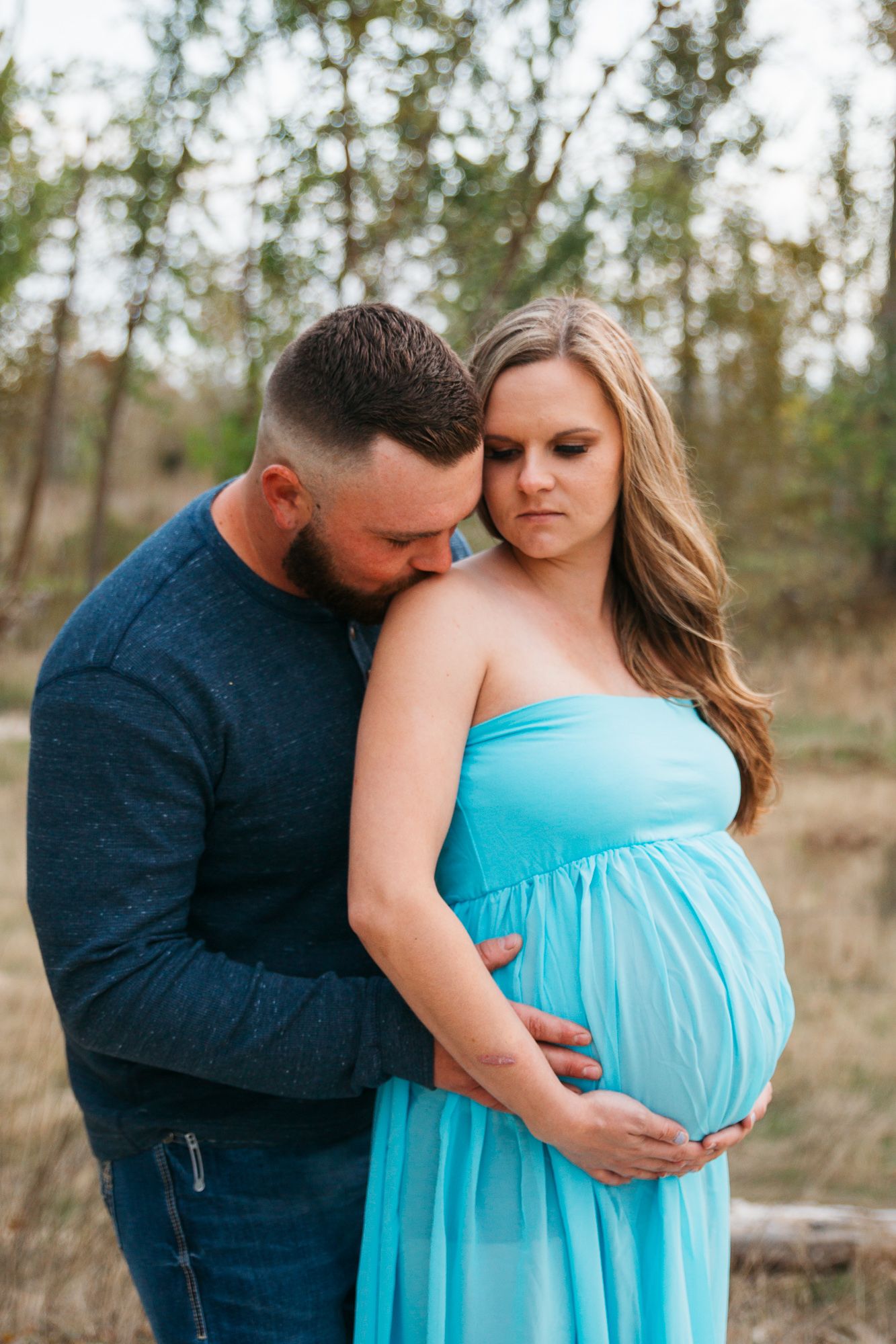 A couple shares an intimate maternity photo session outdoors wearing a turquoise dress and navy shirt - Maternity session in Boise, Idaho