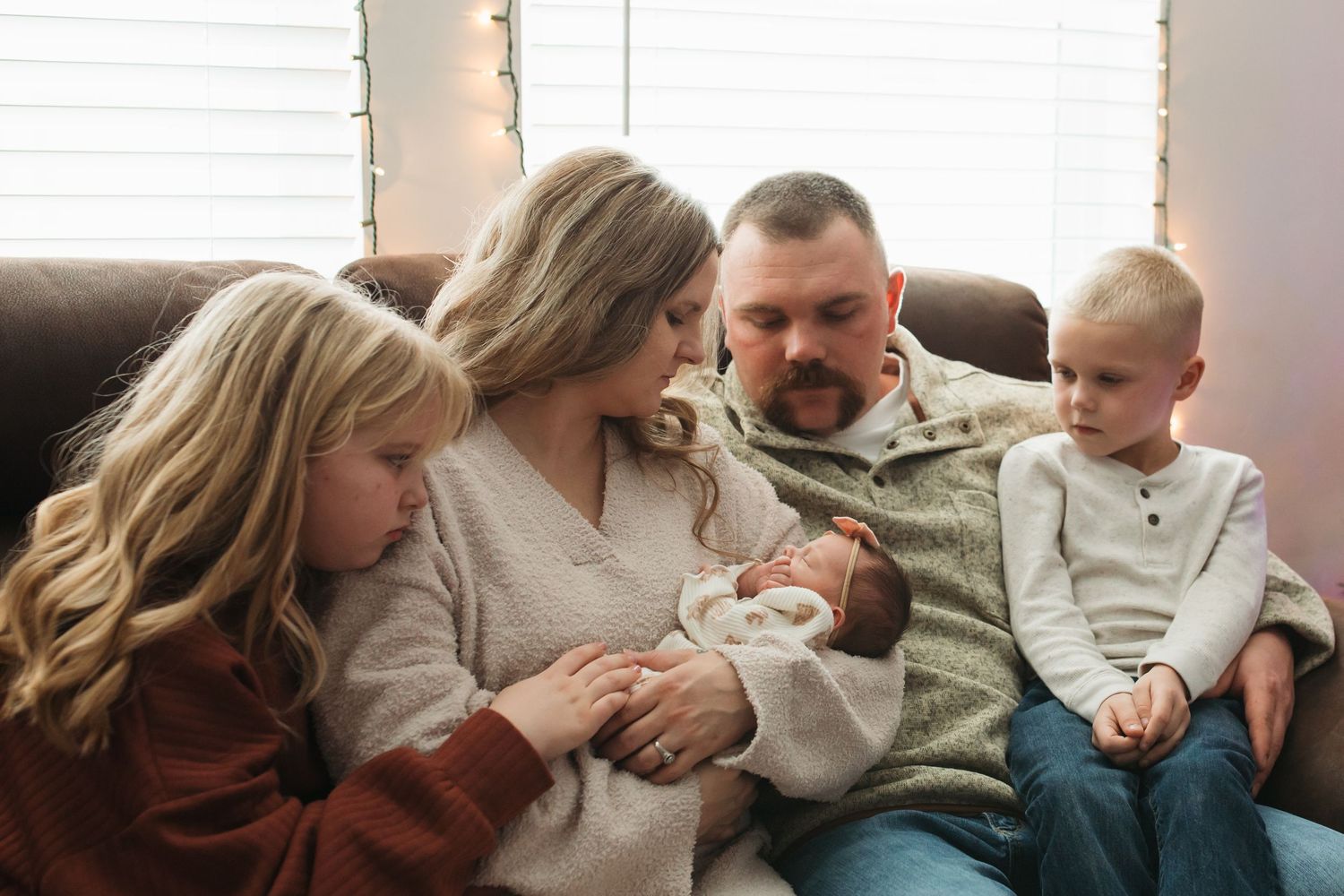 Family snuggling their newborn on the couch during a cozy in-home lifestyle session in Middleton, Idaho.