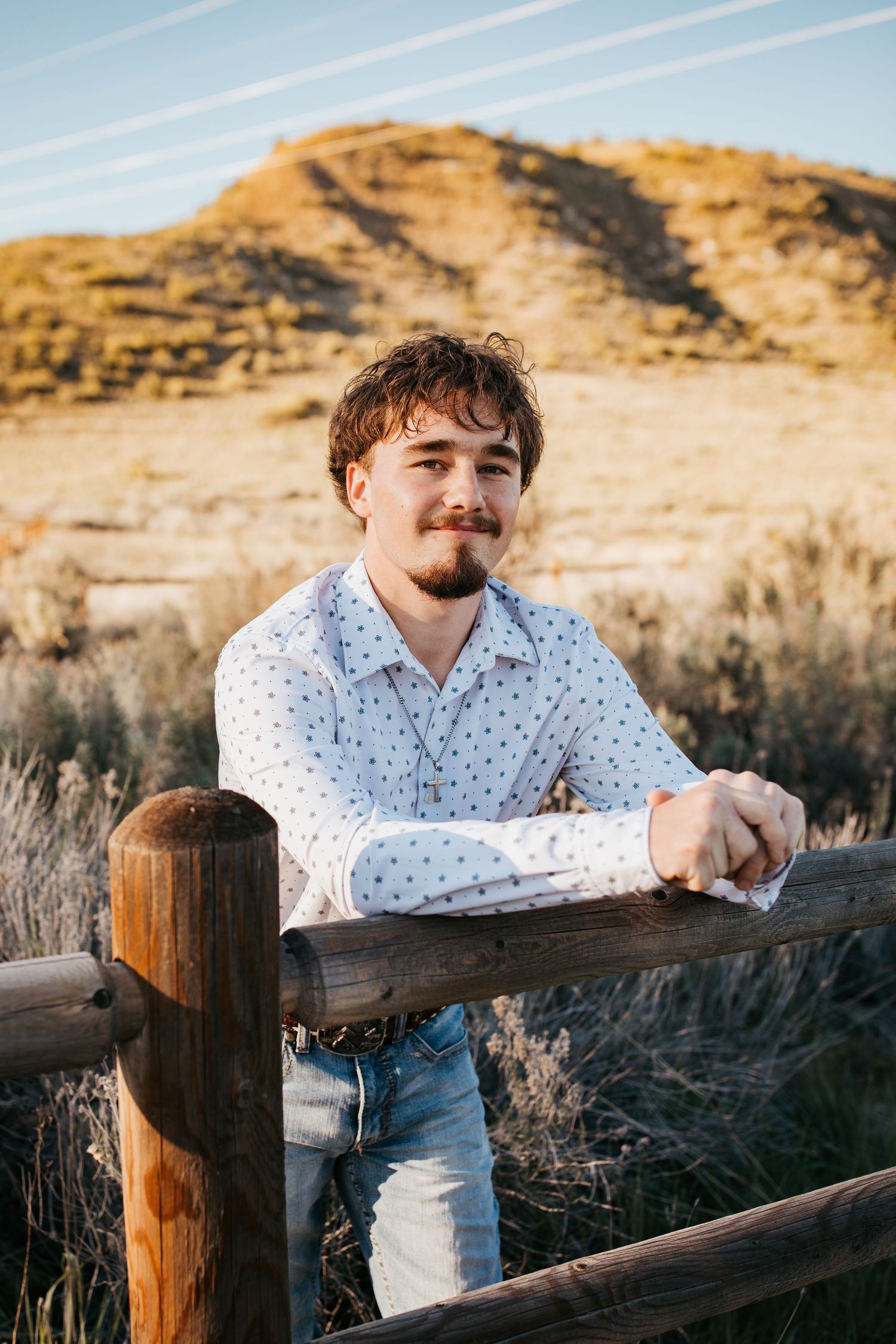 High school senior boy leaning on wooden fence during outdoor Boise Idaho senior photo session