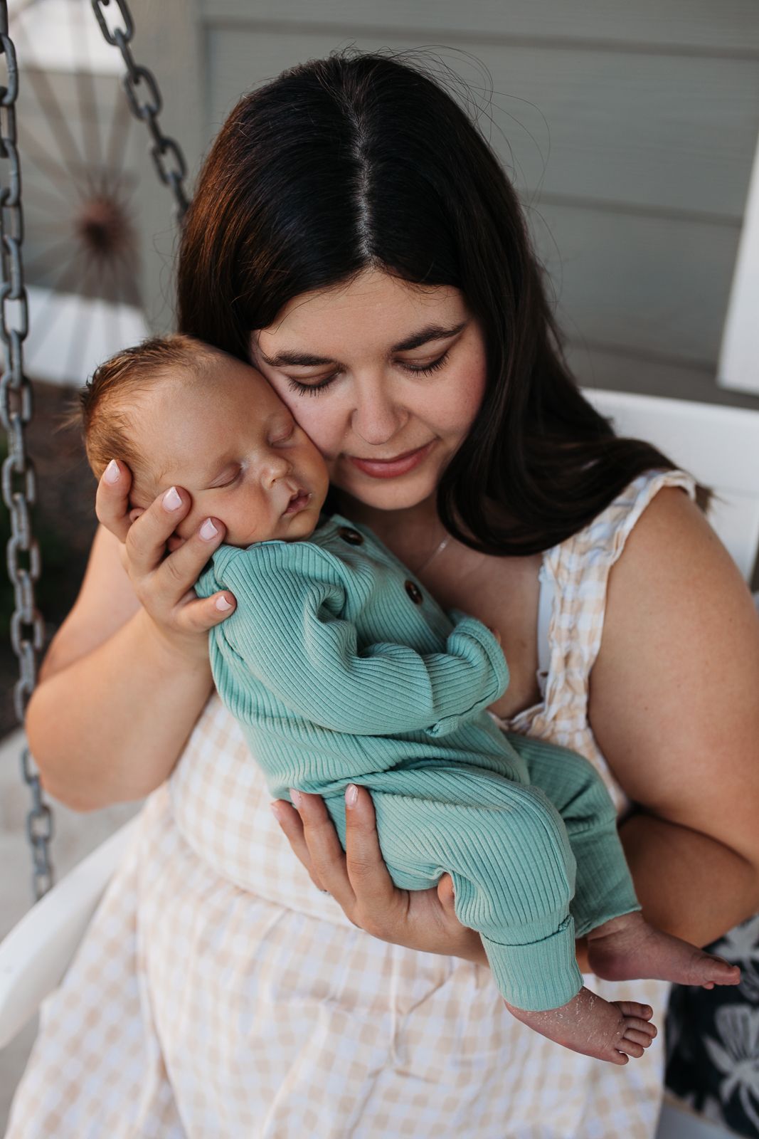 A tender moment between parent and child in matching white and mint green outfits sharing affectionate snuggle - lifestyle in-home newborn