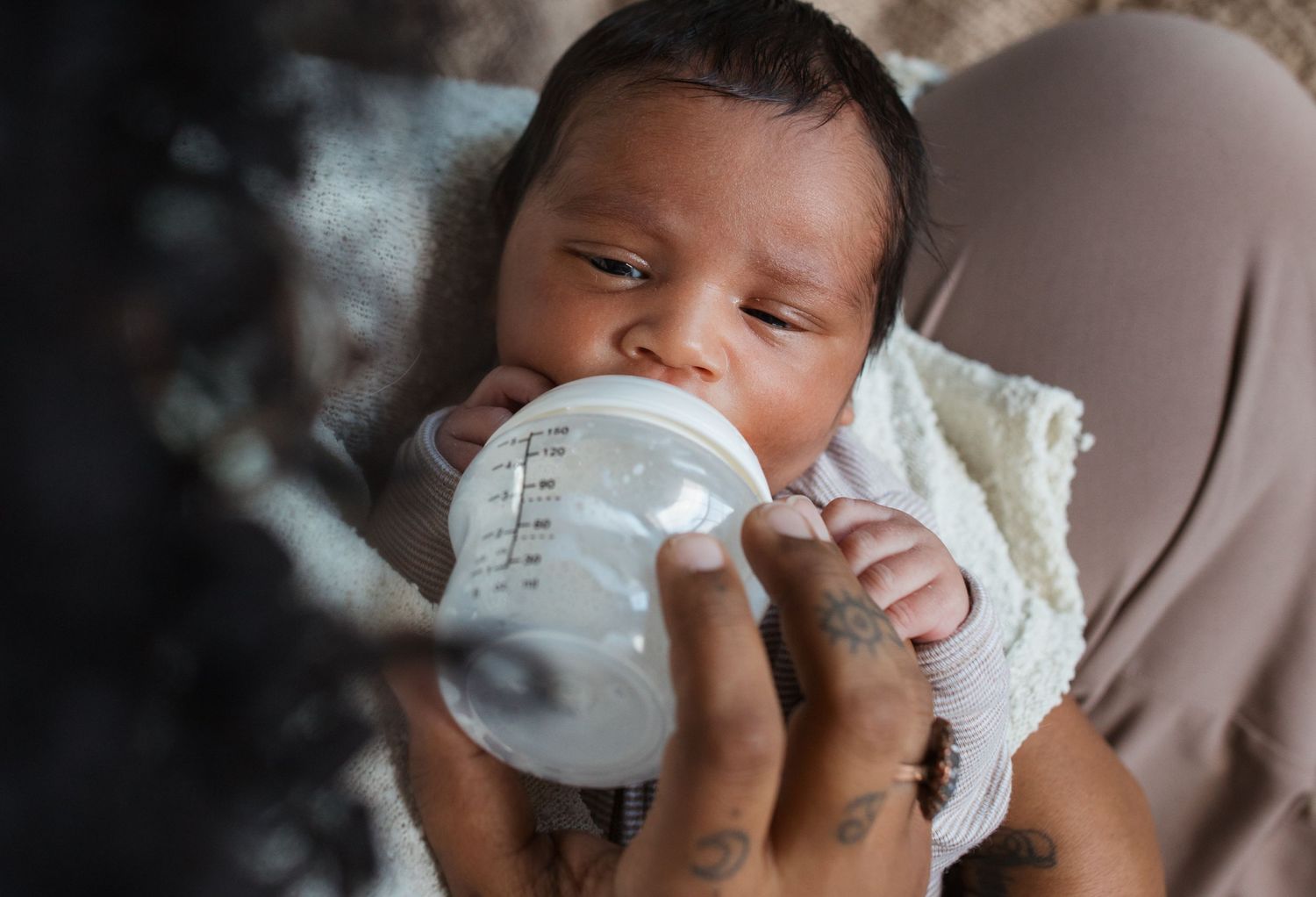 Newborn baby being bottle fed by mother during a lifestyle newborn photography session in the Treasure Valley.