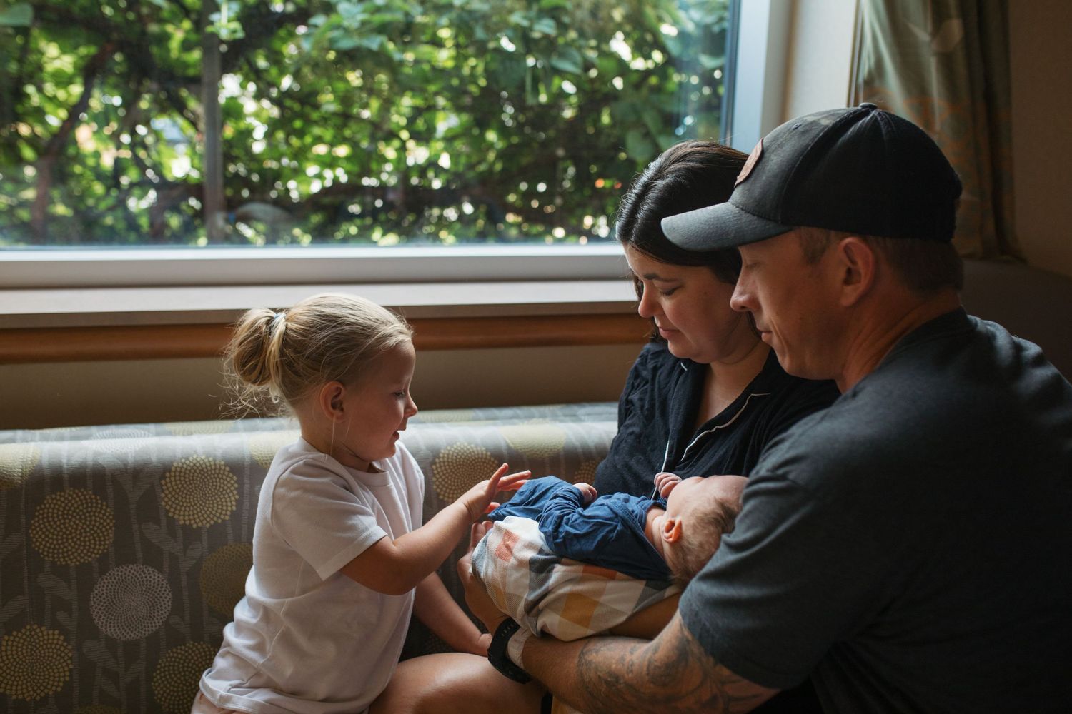 A mom and dad holding a newborn baby introducing a sibling - Fresh 48 session in Boise, Idaho
