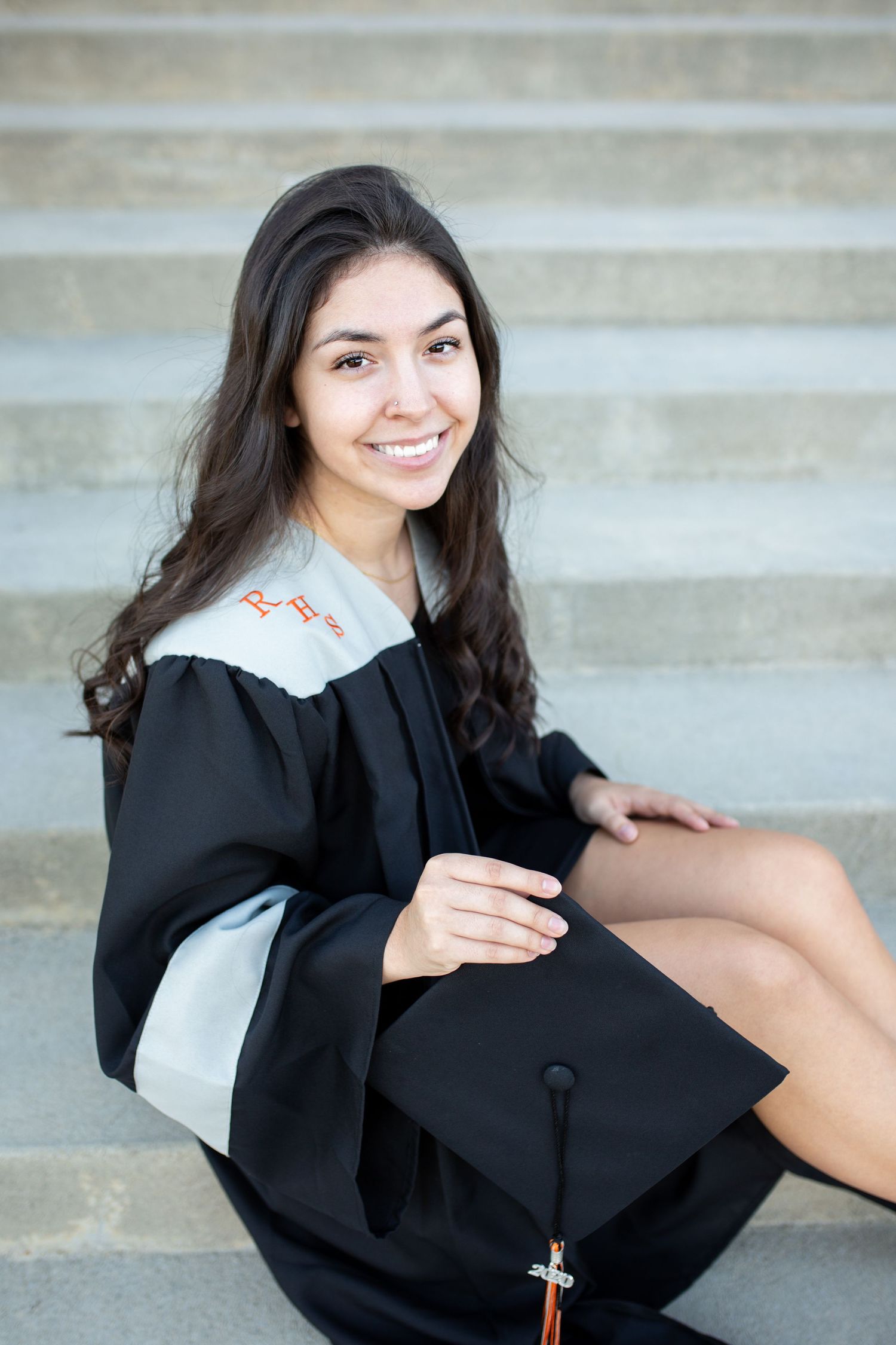 Senior girl graduation portrait sitting on steps in cap and gown