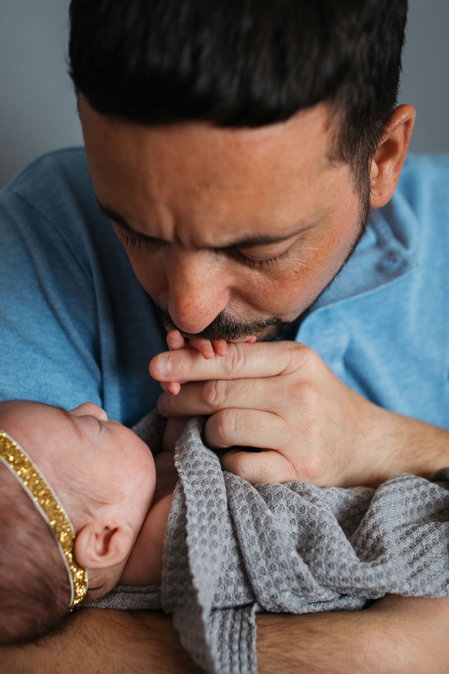Dad gently kissing his newborn baby girl’s hand during a studio newborn session in Nampa, Idaho