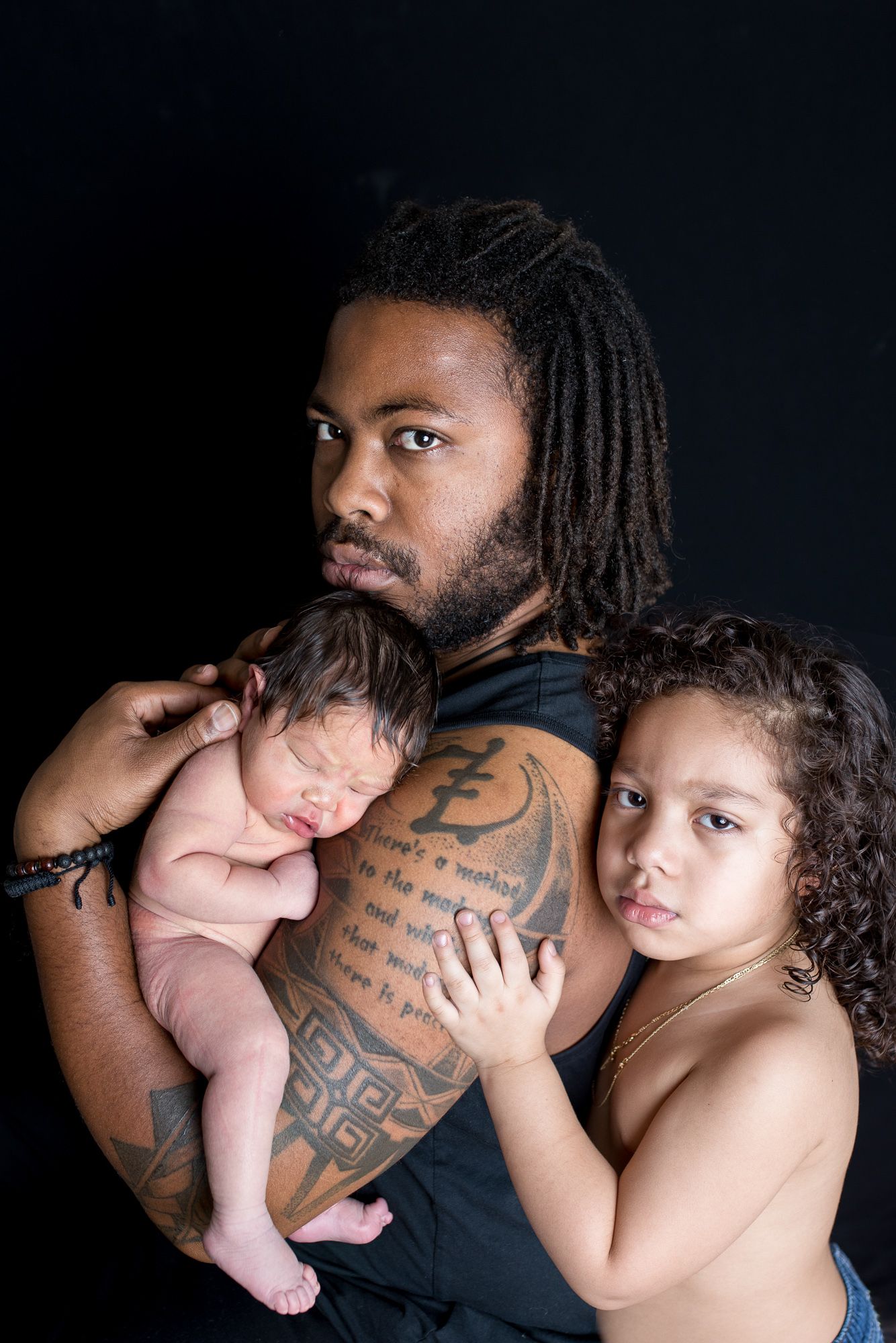 A series of intimate black and white photos showing a parent holding a small baby against a dark background studio newborn photography Nampa