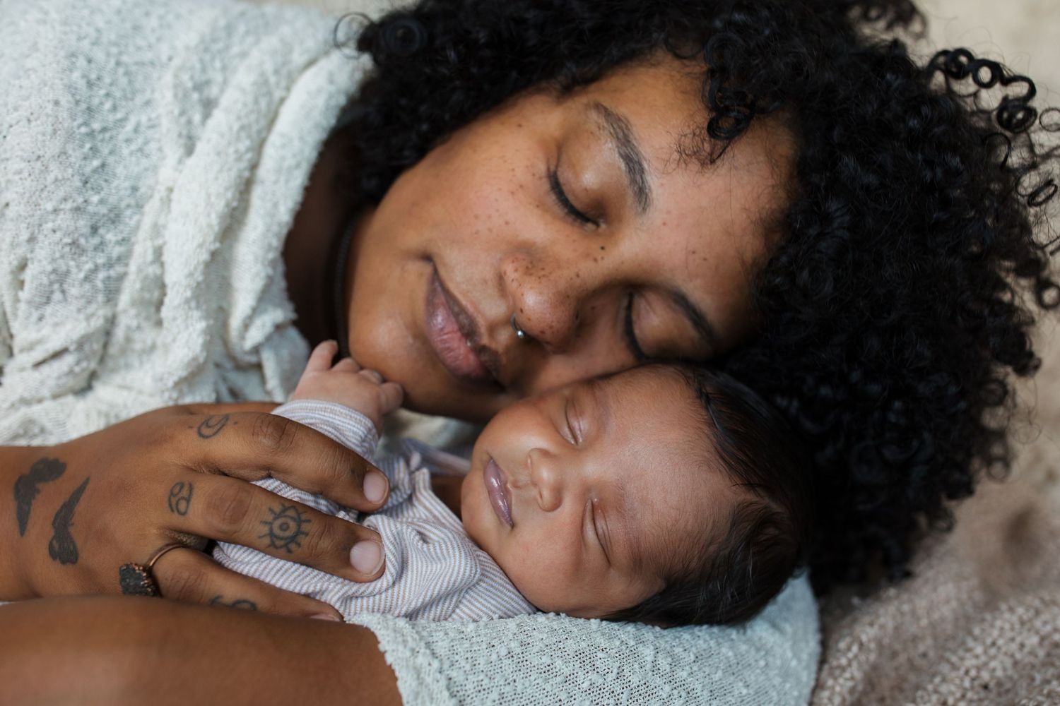 Mother resting with her sleeping newborn baby during a lifestyle newborn photography session in the Treasure Valley.