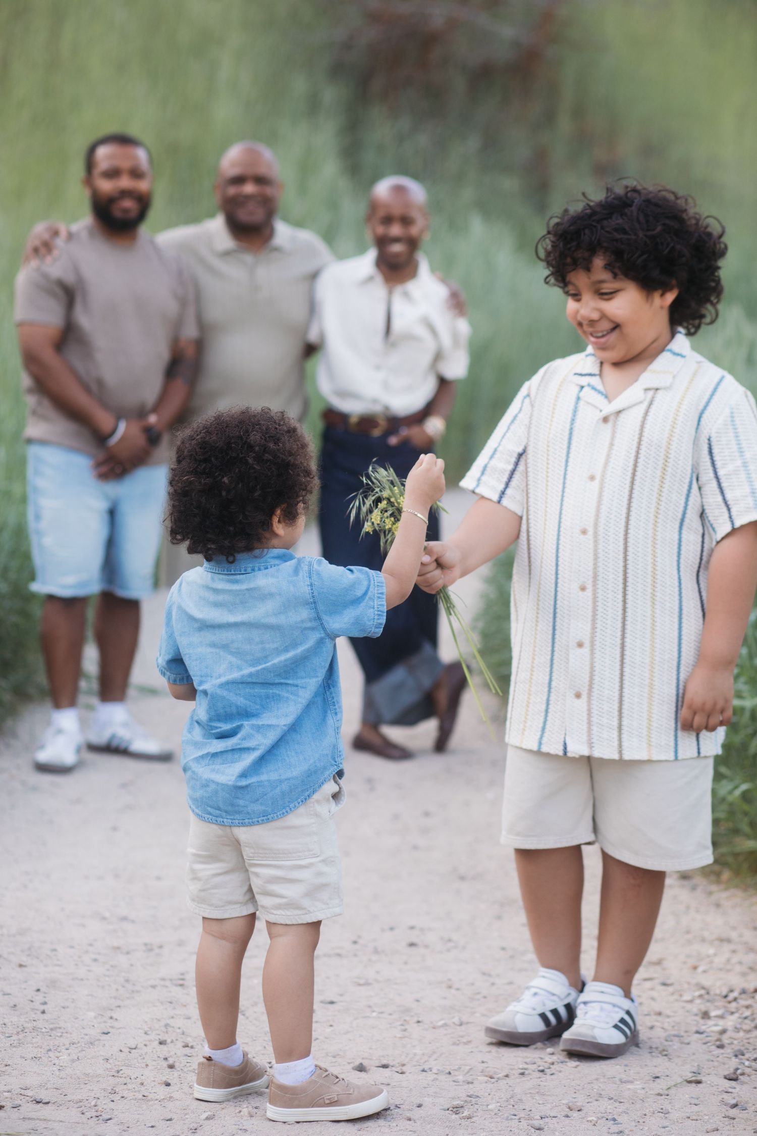 Siblings holding hands during a candid extended family session at Camel’s Back Park with family smiling in the background.
