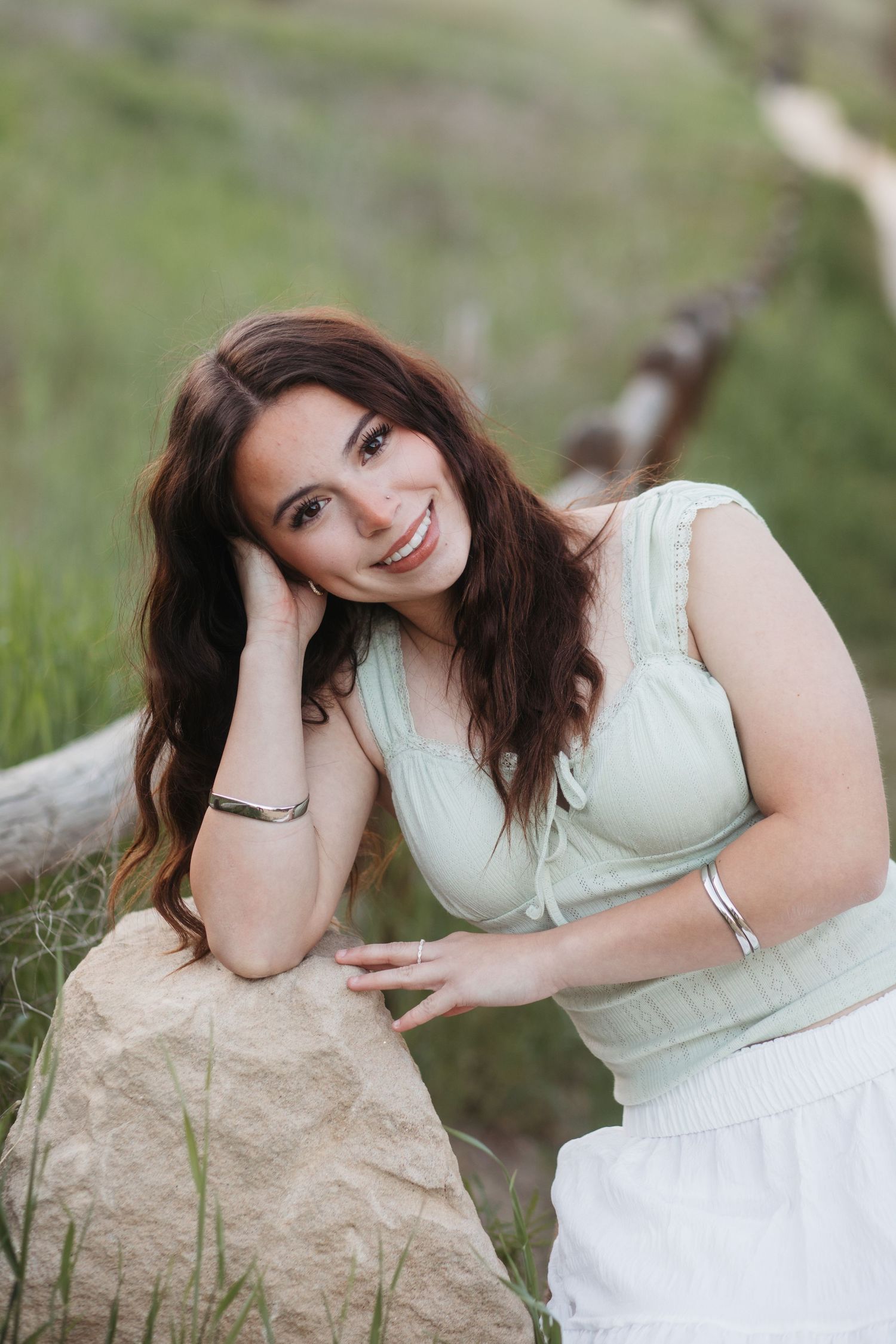 High school senior leaning on rock and smiling during Boise senior photo session