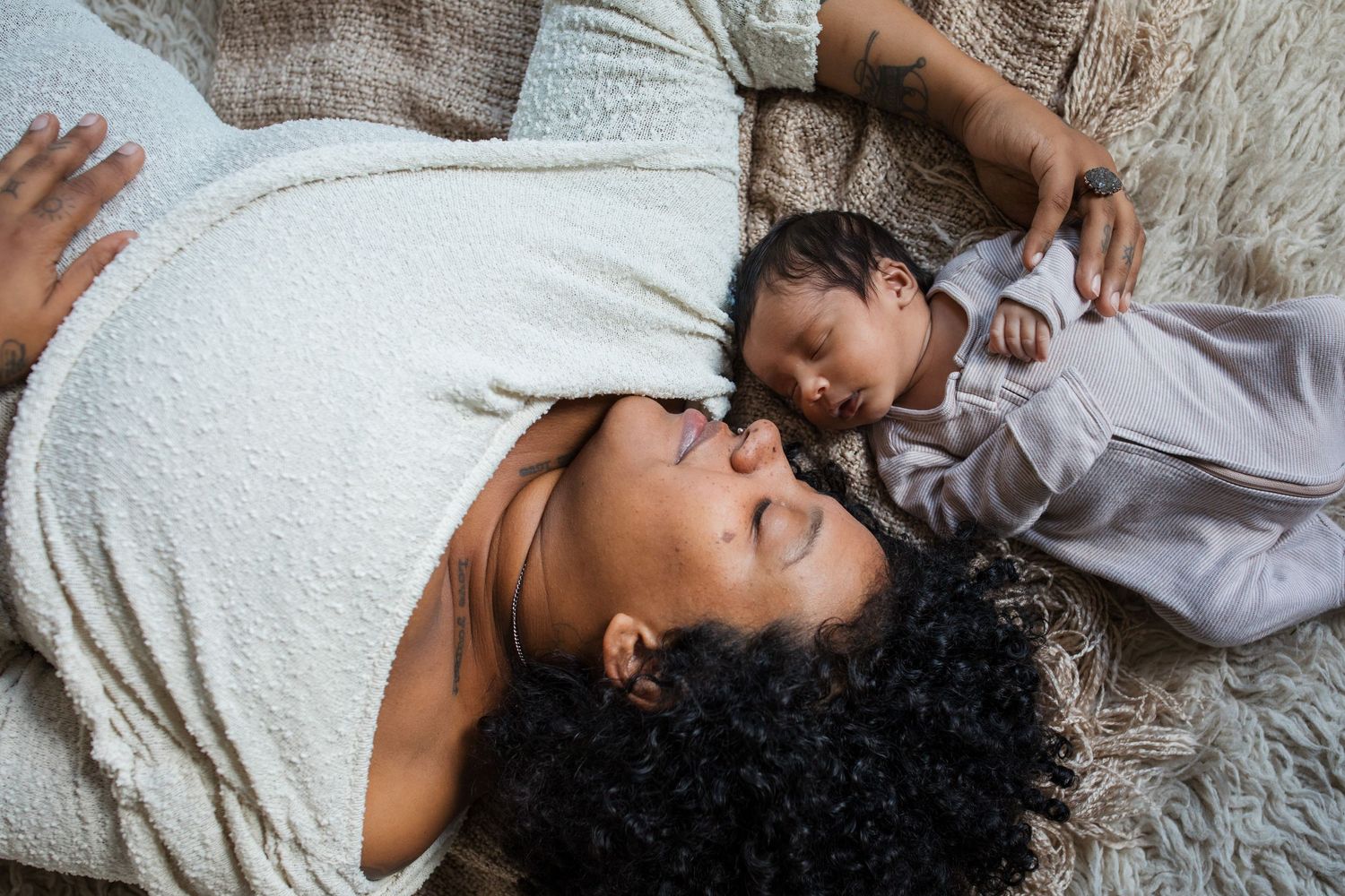 Mother lying beside her sleeping newborn baby during a lifestyle newborn photography session in the Treasure Valley.