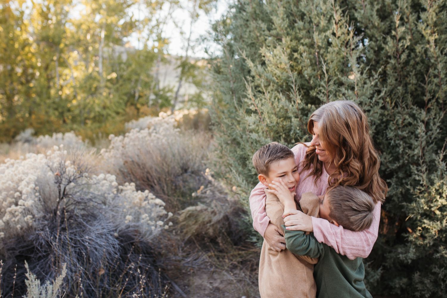A series of tender moments between a parent and child playing outdoors in autumn with greenery in the background. Boise foothills family pho