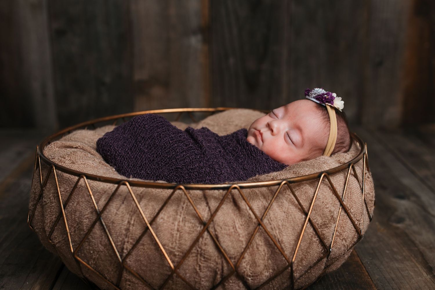 Newborn baby girl wrapped in purple during a studio newborn session in Nampa, Idaho