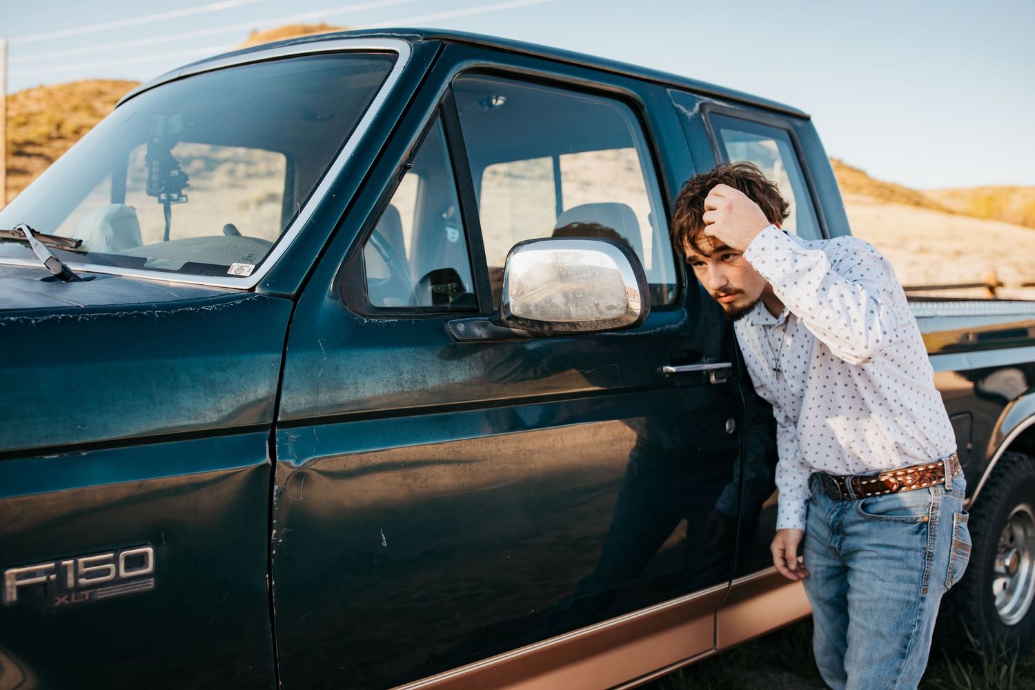 High school senior boy standing by truck adjusting hair during Boise Idaho senior photo session
