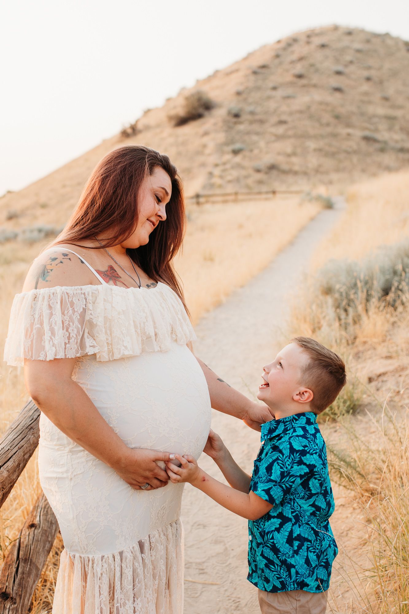A tender moment between parent and child against a golden hillside backdrop wearing white and turquoise - Maternity session in Boise, Idaho