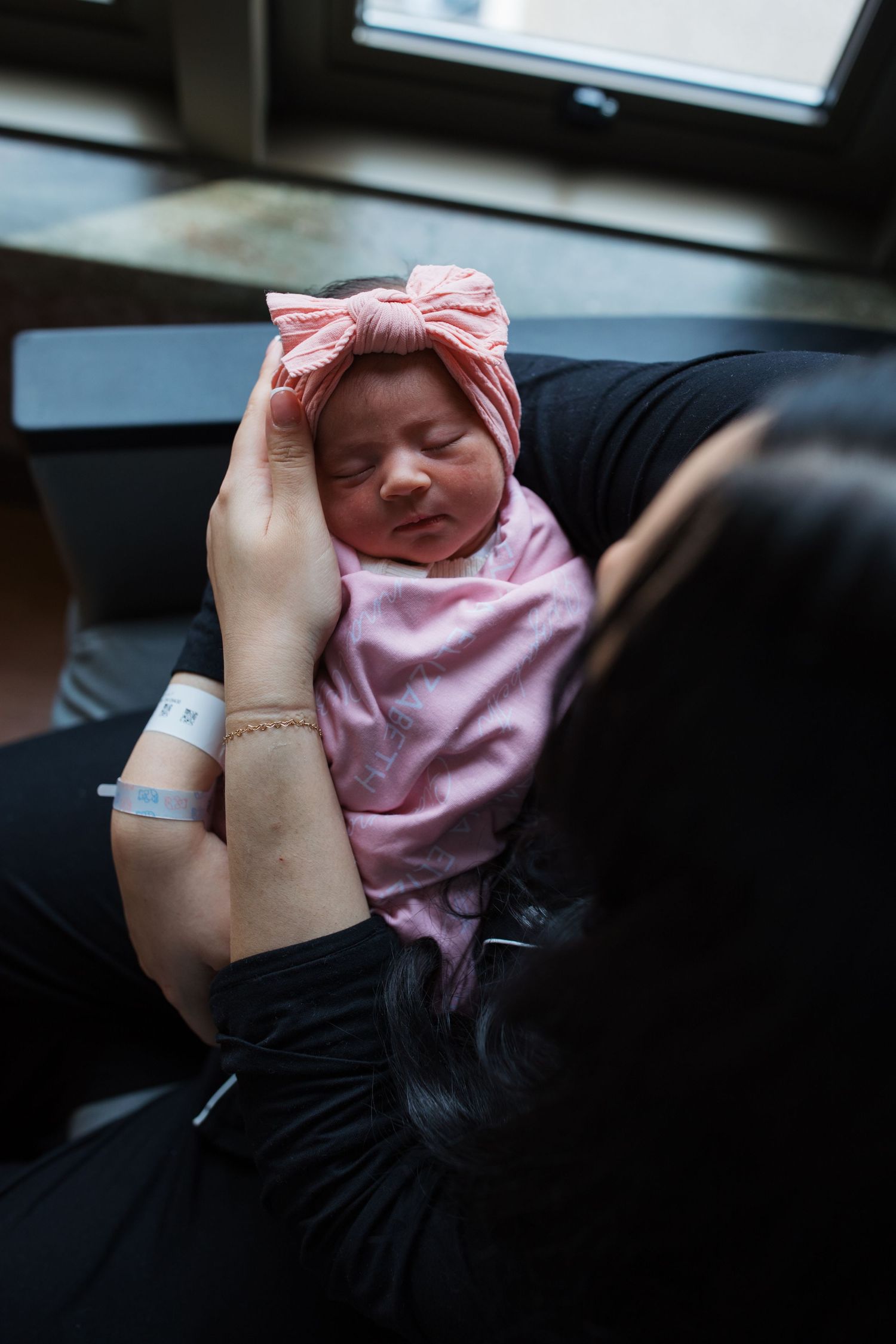 Mother holding newborn baby girl by hospital window during Boise Fresh 48 photography
