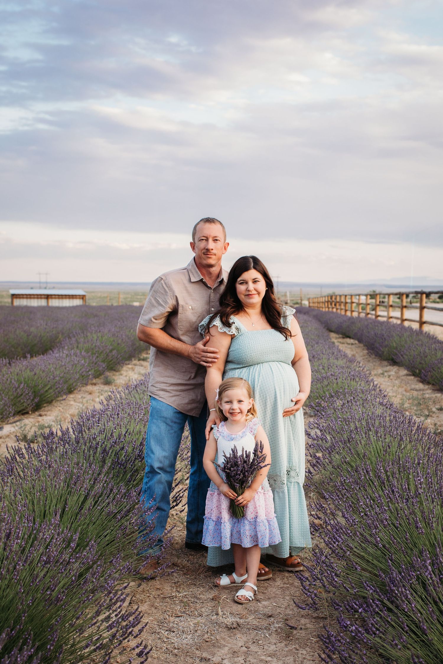 Expectant parents holding a bouquet of lavender during a summer maternity photography session in Idaho.