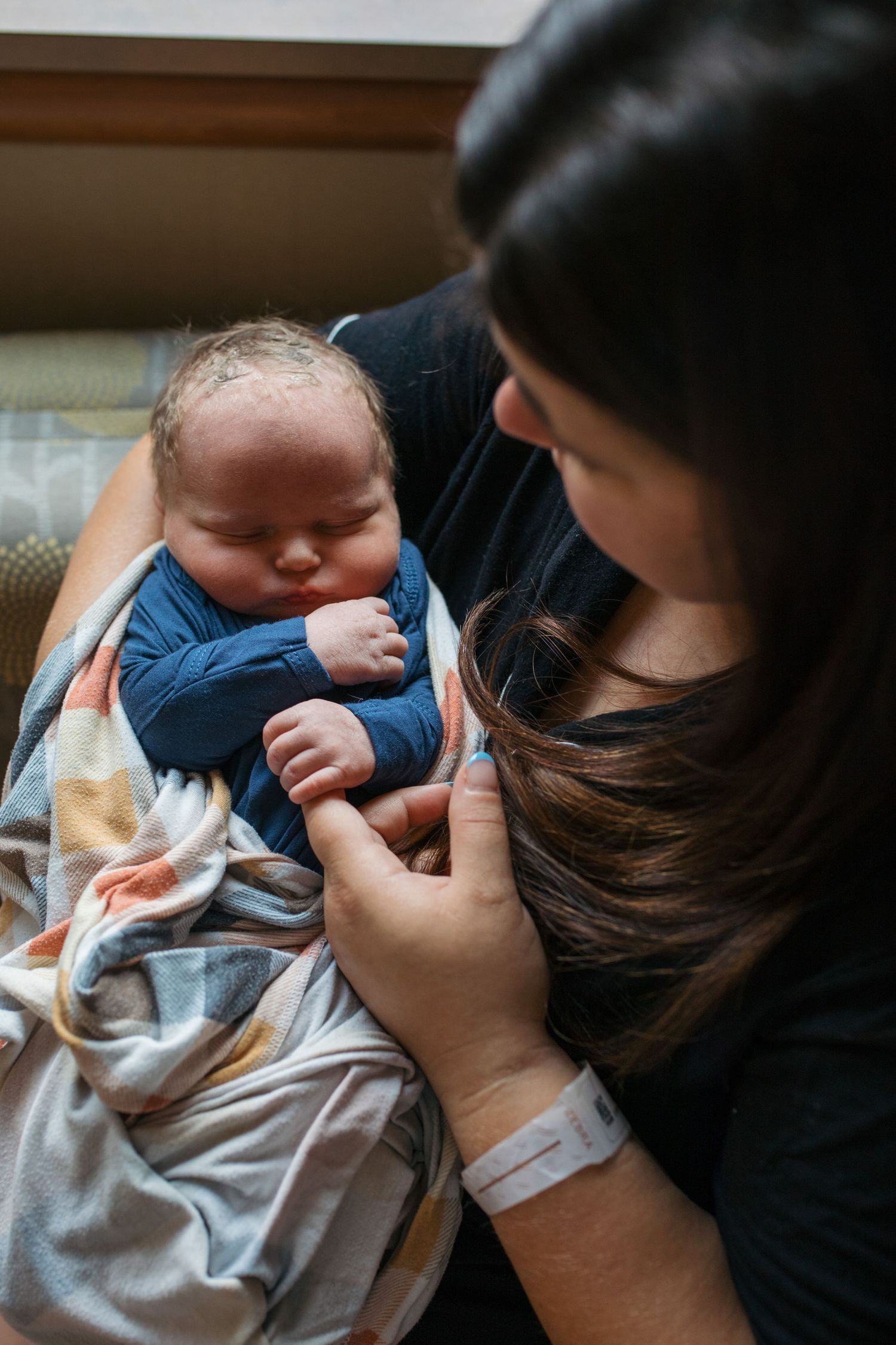 A mother holding her infant and the infant griping the mothers finger - Fresh 48 session in Boise, Idaho
