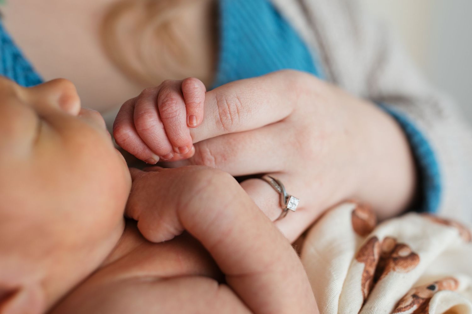 Close-up of newborn baby boy’s tiny hand holding his mother’s finger during studio newborn session
