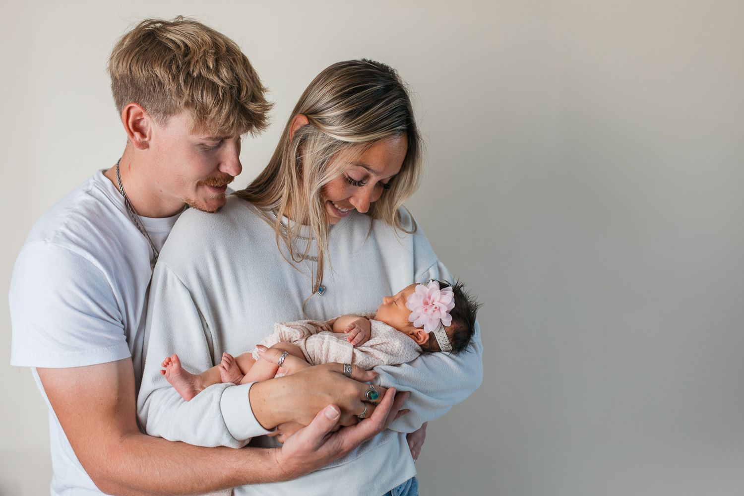 A series of tender moments showing parents cradling and bonding with their newborn baby in a light-filled room.  studio newborn photography