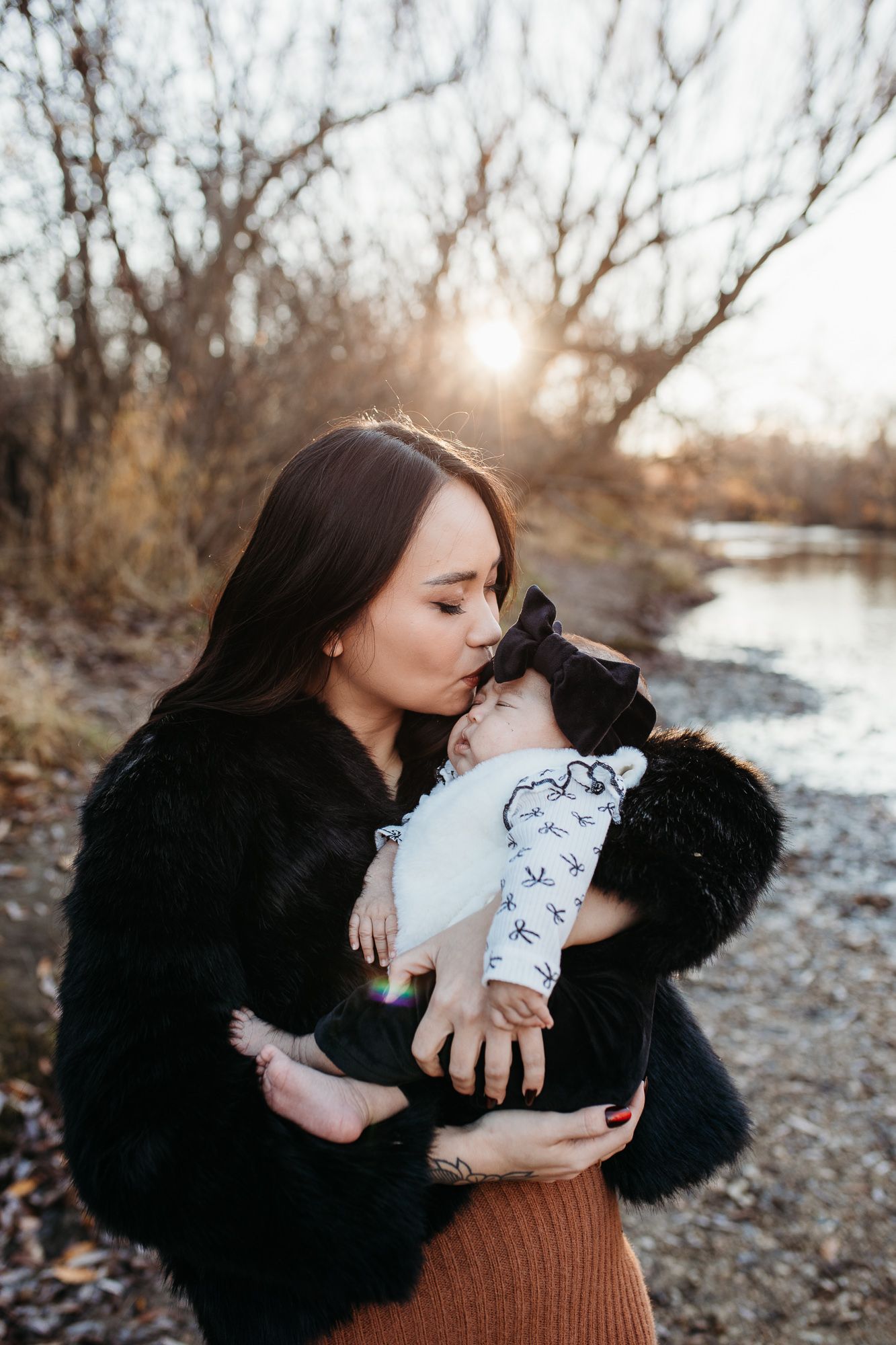 A person in a black sweater shares tender moments with their infant outdoors in winter - lifestyle family photos in Boise