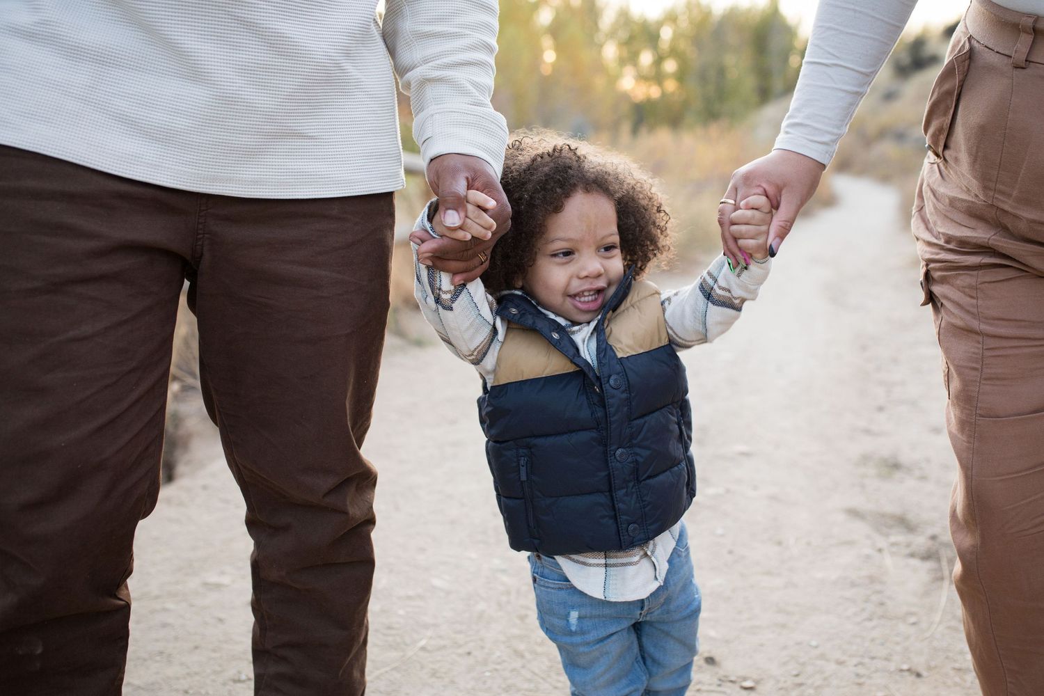 Toddler holding hands with parents during a fall family photography session in Boise, Idaho.