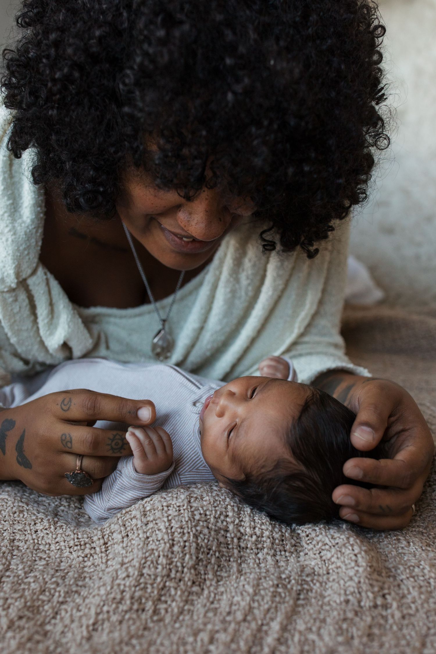 Mother smiling down at her newborn baby during a lifestyle newborn photography session in the Treasure Valley.