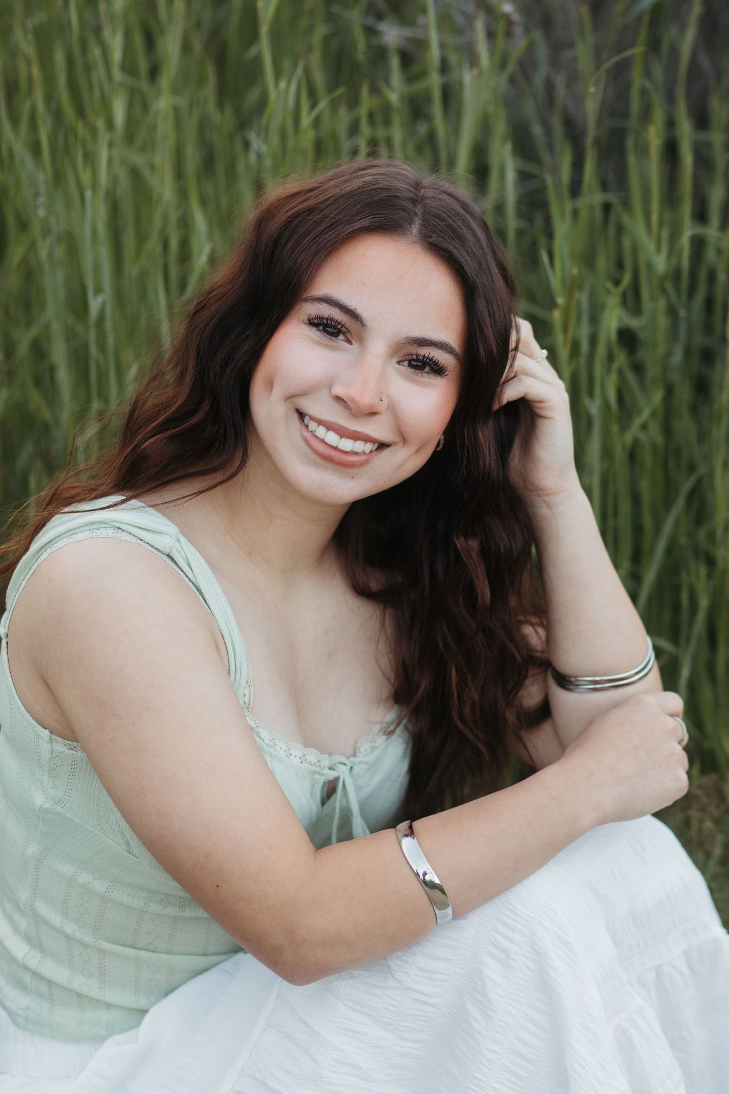 Senior girl with long hair posing in a field with natural light for Boise senior pictures